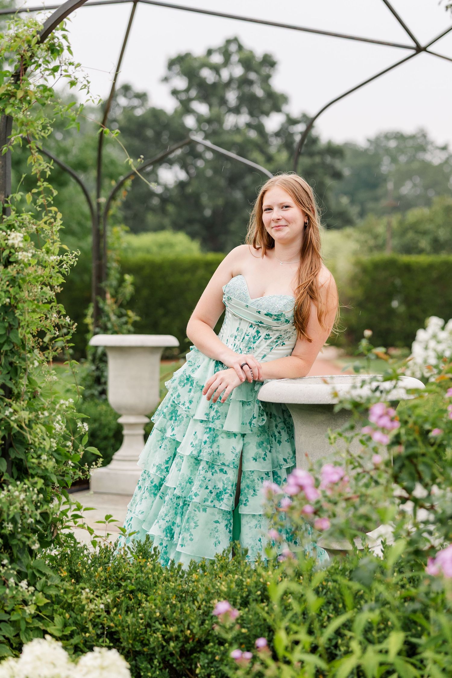 Whimsical senior portrait of Samantha standing among colorful summer flowers at Cantigny Park.