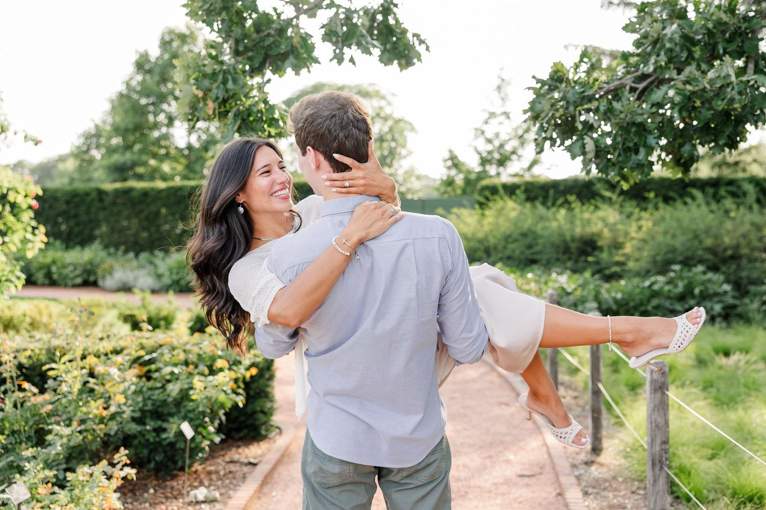 Jack carries a smiling Alysia past the blooming gardens after their surprise proposal.