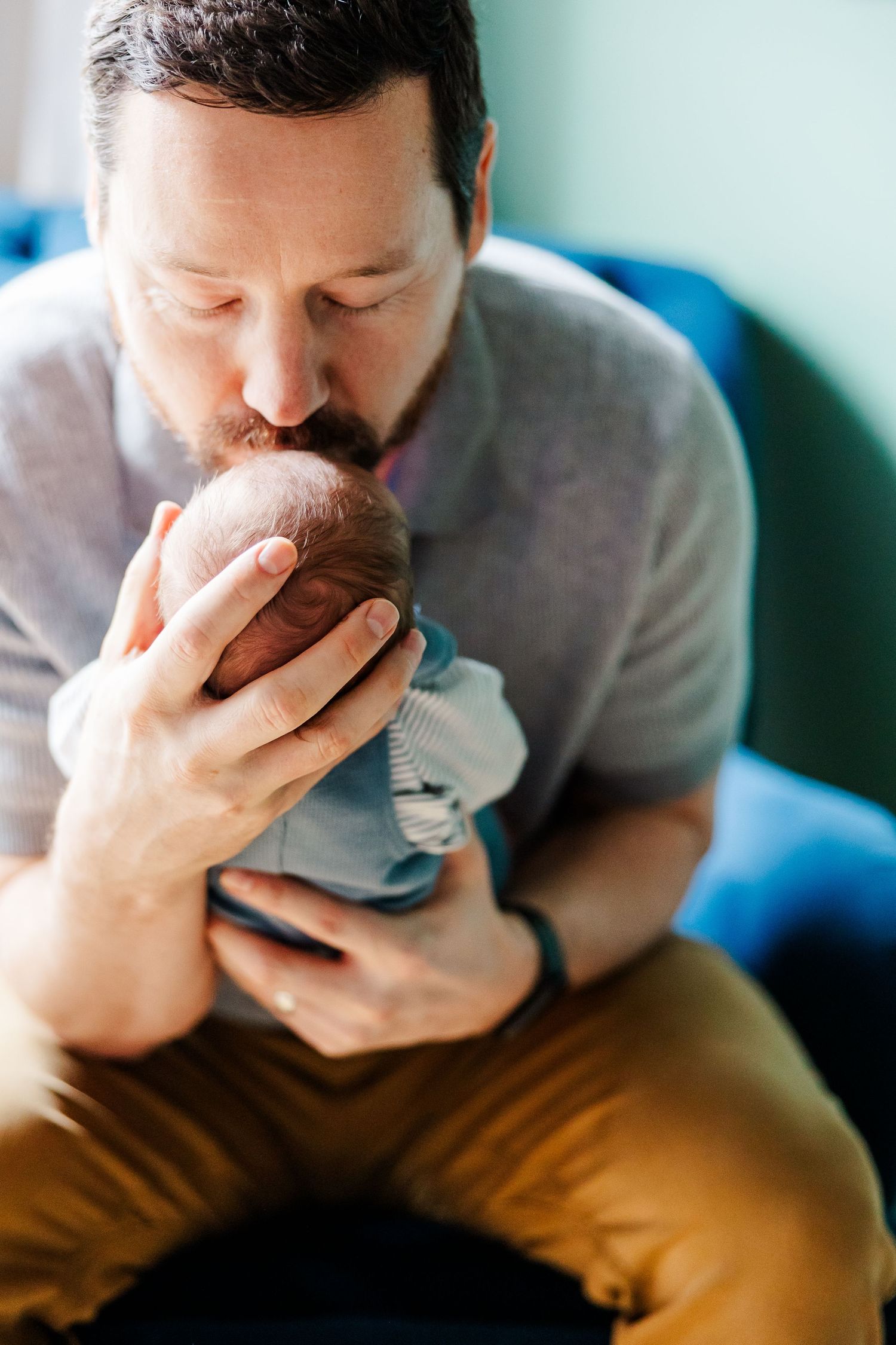 Father kisses newborn son during bright in-home lifestyle newborn session in Crystal Lake, Illinois