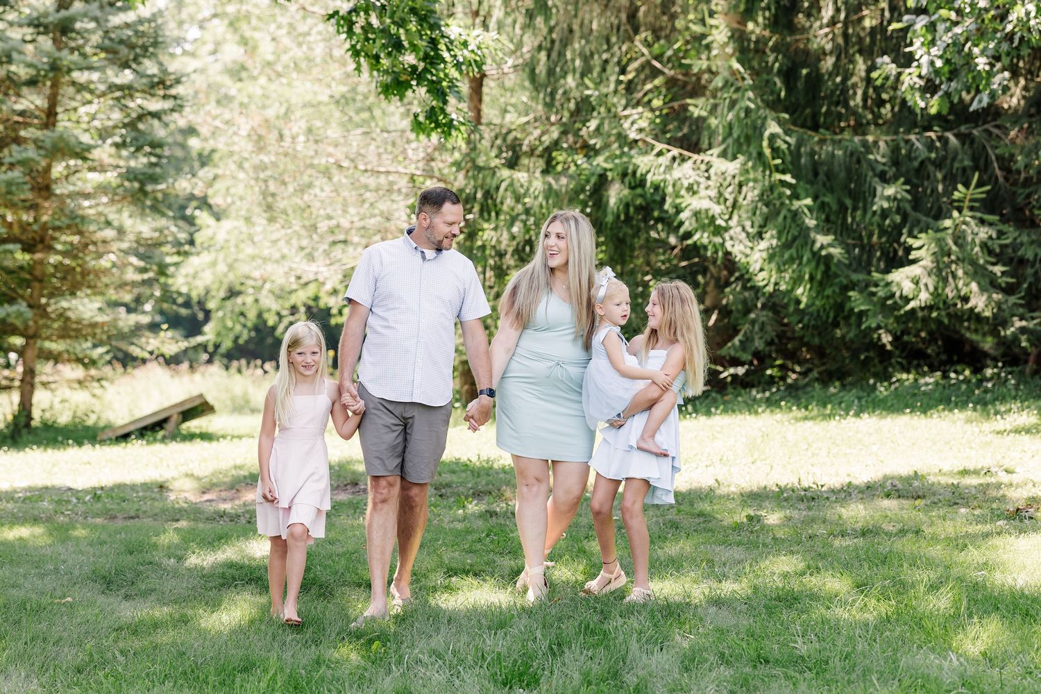 Parents and daughters walking together during a summer family portrait session in Crystal Lake, IL.