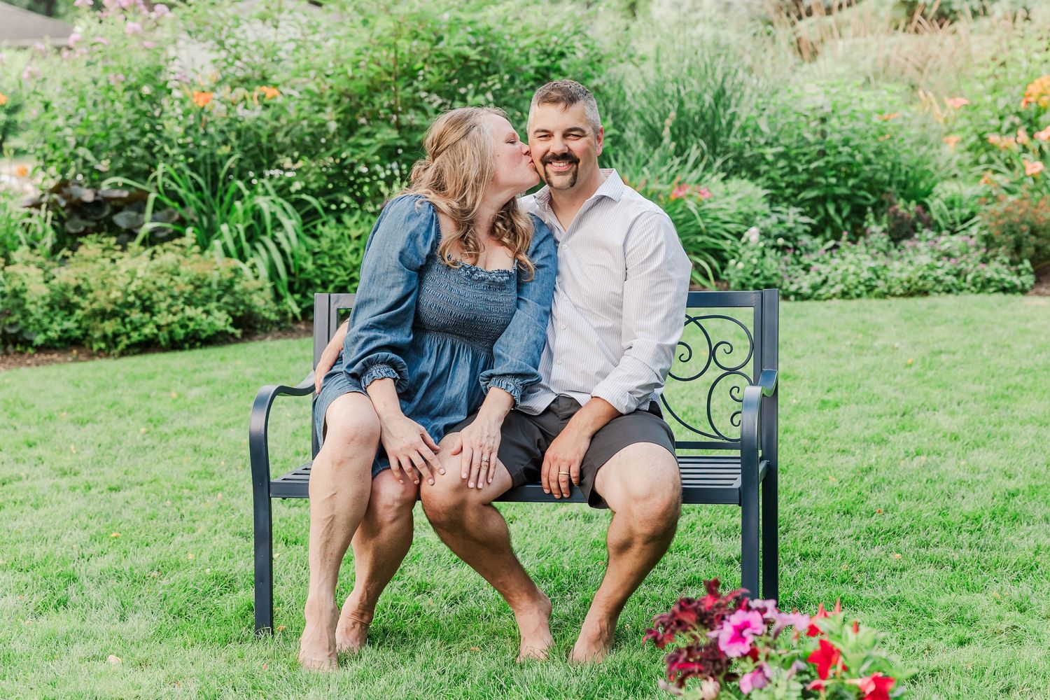 A couple enjoying quality time together on a garden bench with pink flowers nearby.