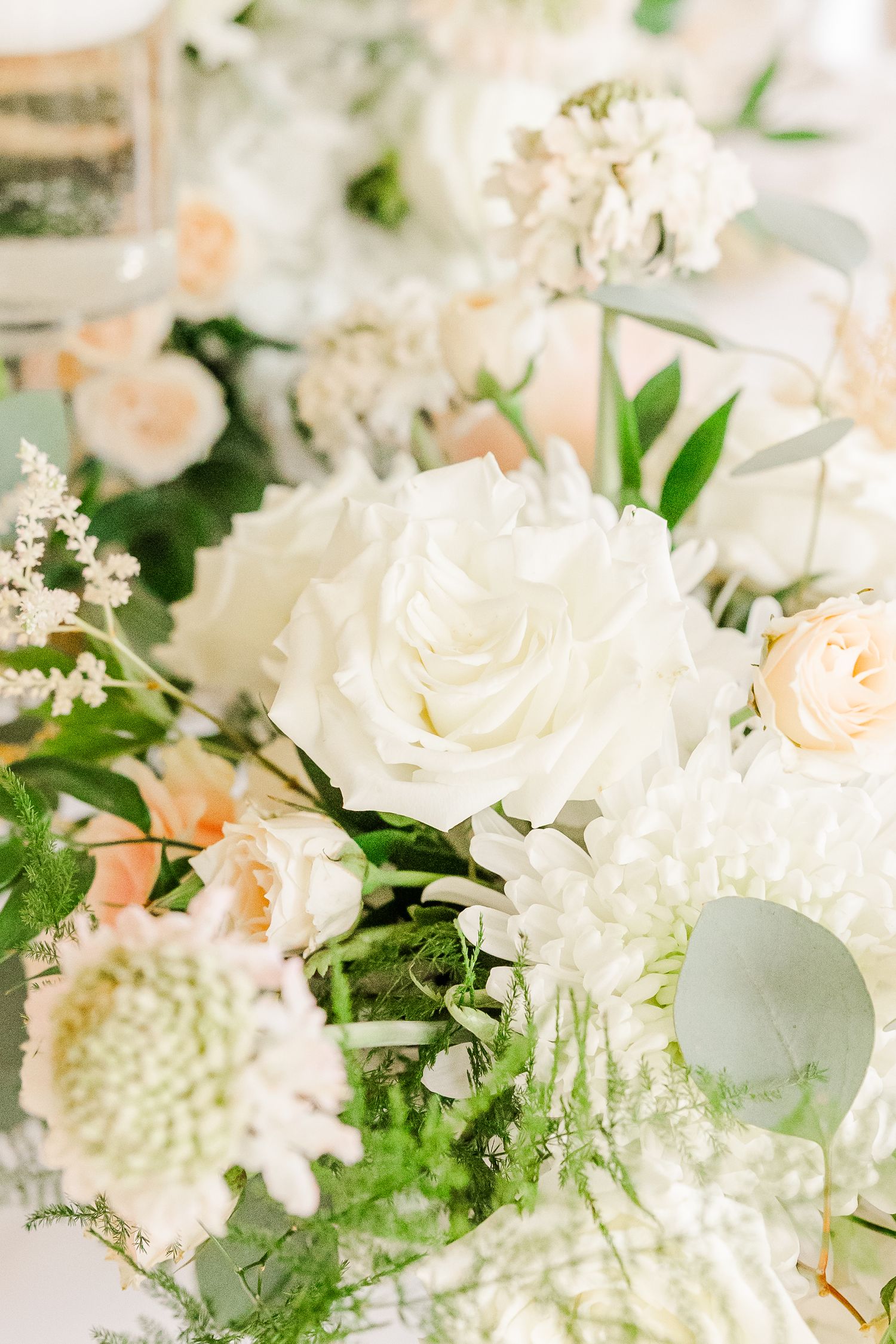 Close-up of white and blush roses with greenery in an elegant floral arrangement.
