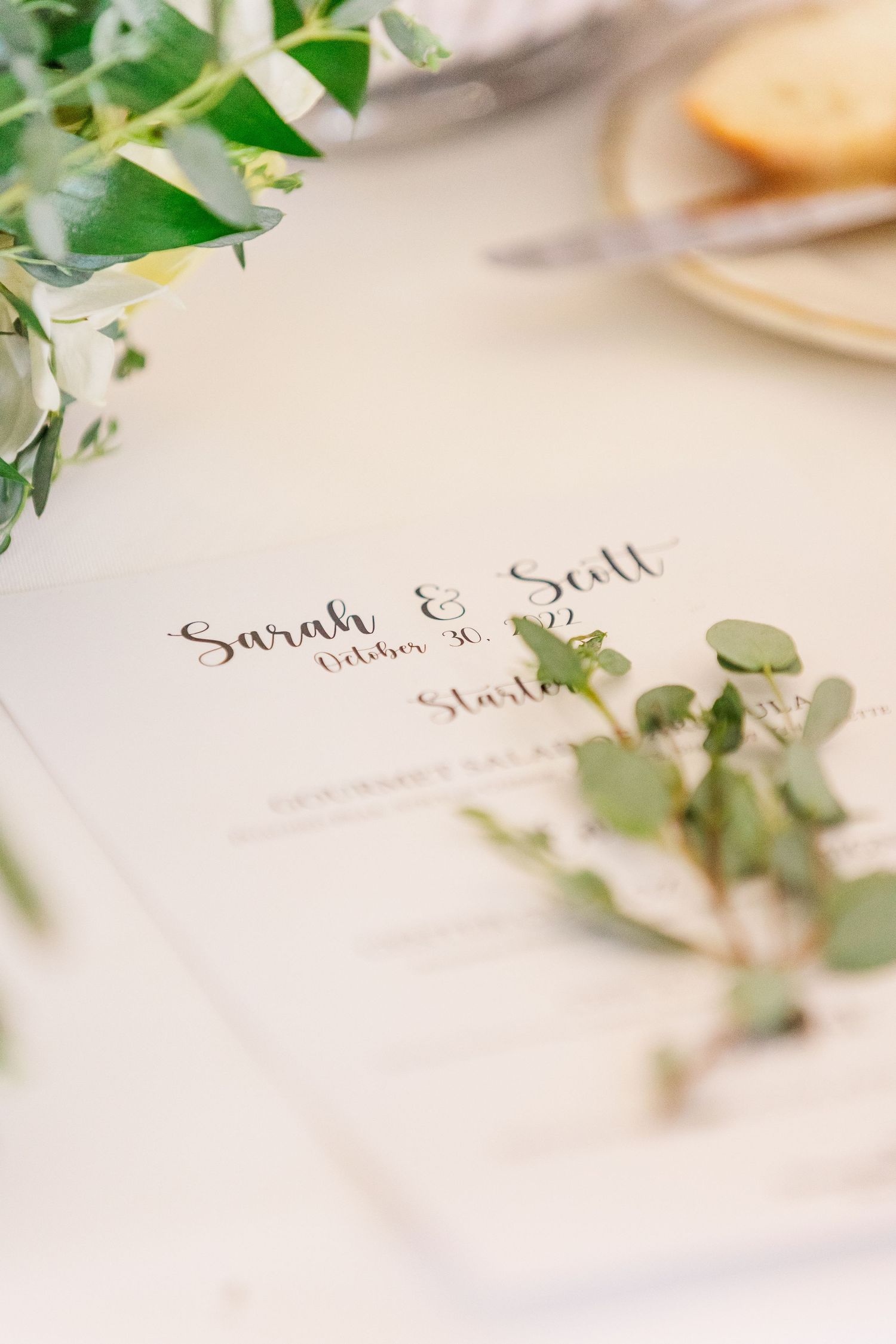 Elegant wedding menu card with greenery and eucalyptus decoration on white surface.