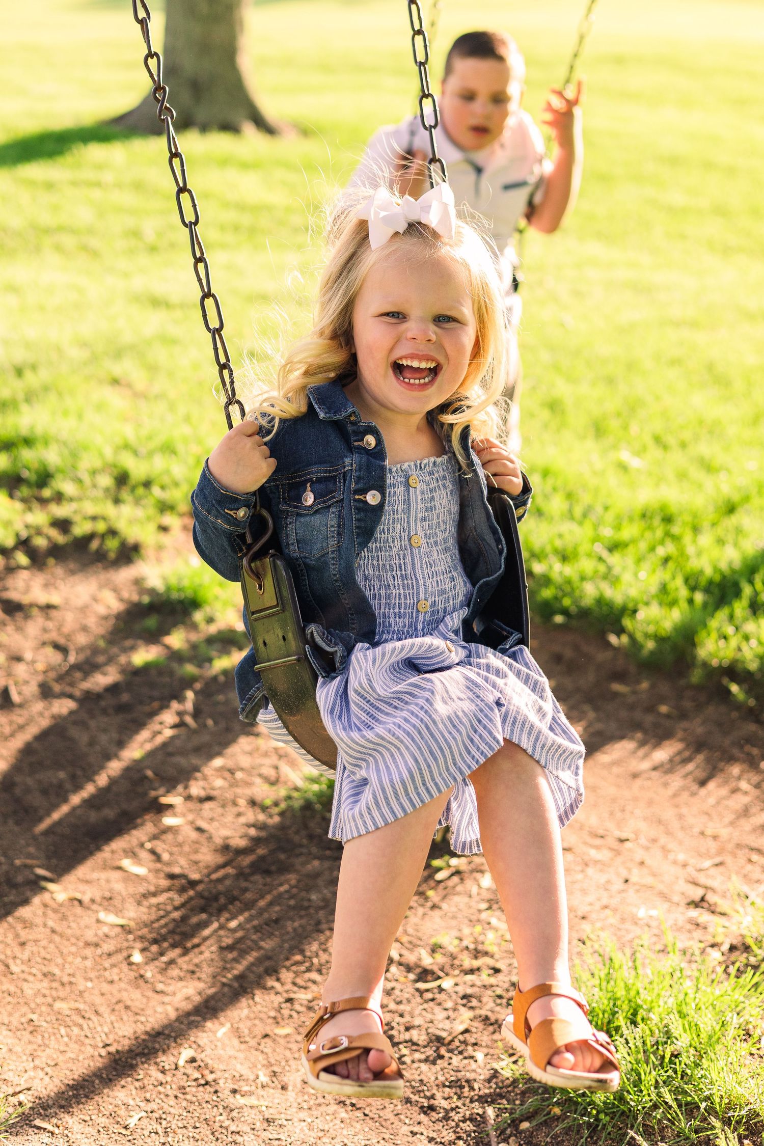 Children enjoying playground swings on sunny day in park setting.