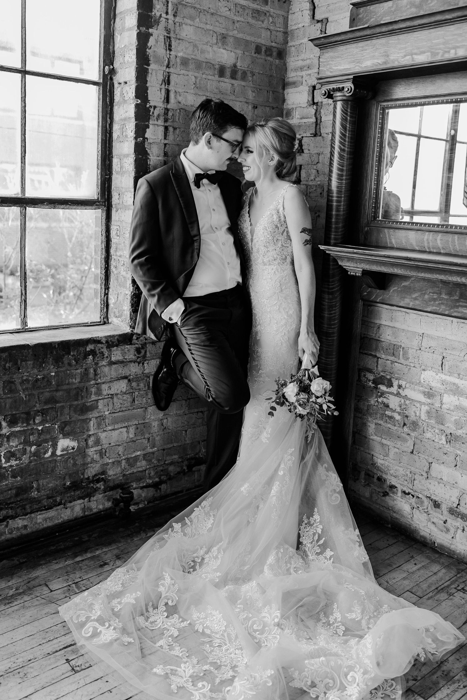 A romantic black and white portrait of a couple in an industrial wedding venue with exposed brick walls.