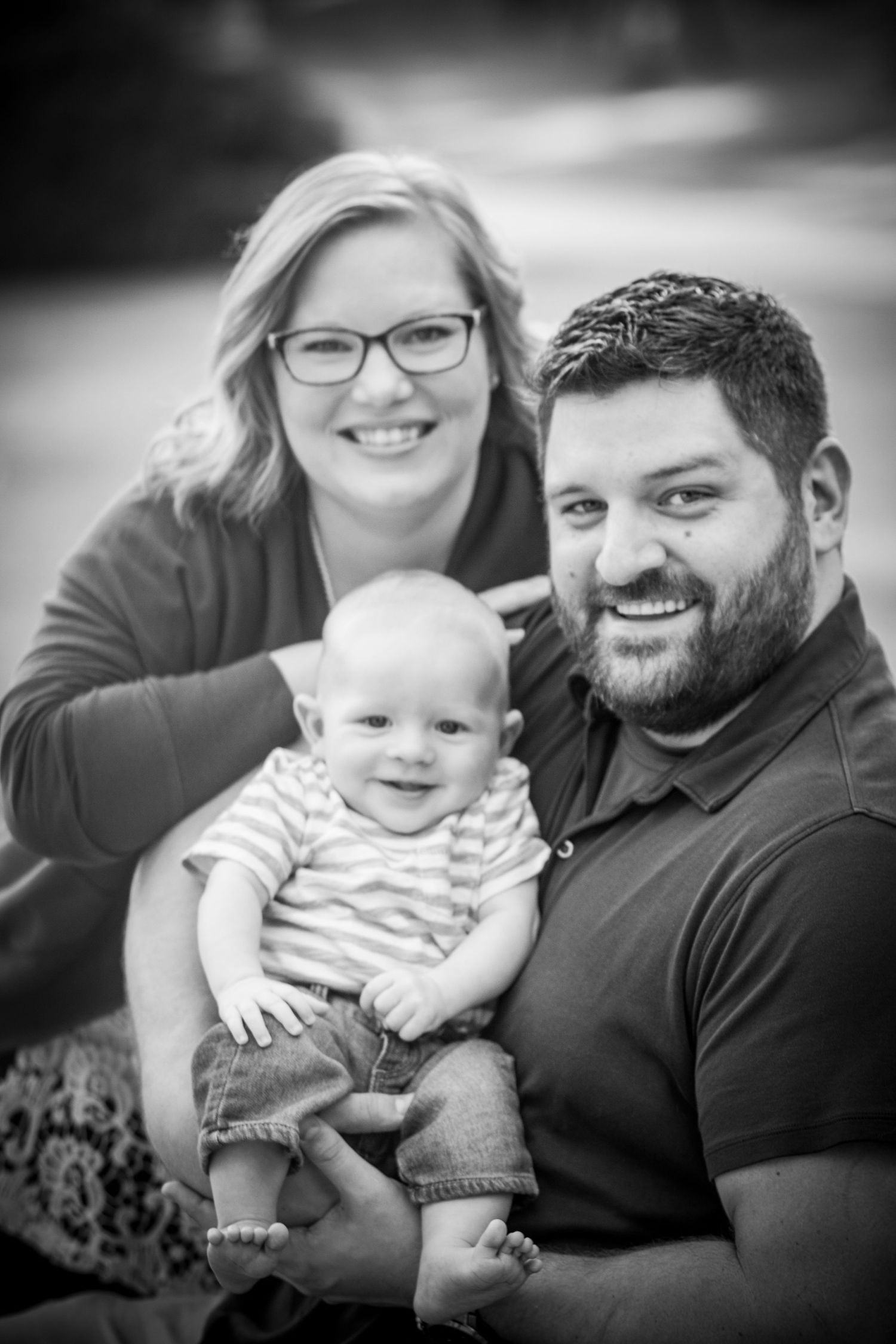 Black and white portrait of a family with infant outdoors.
