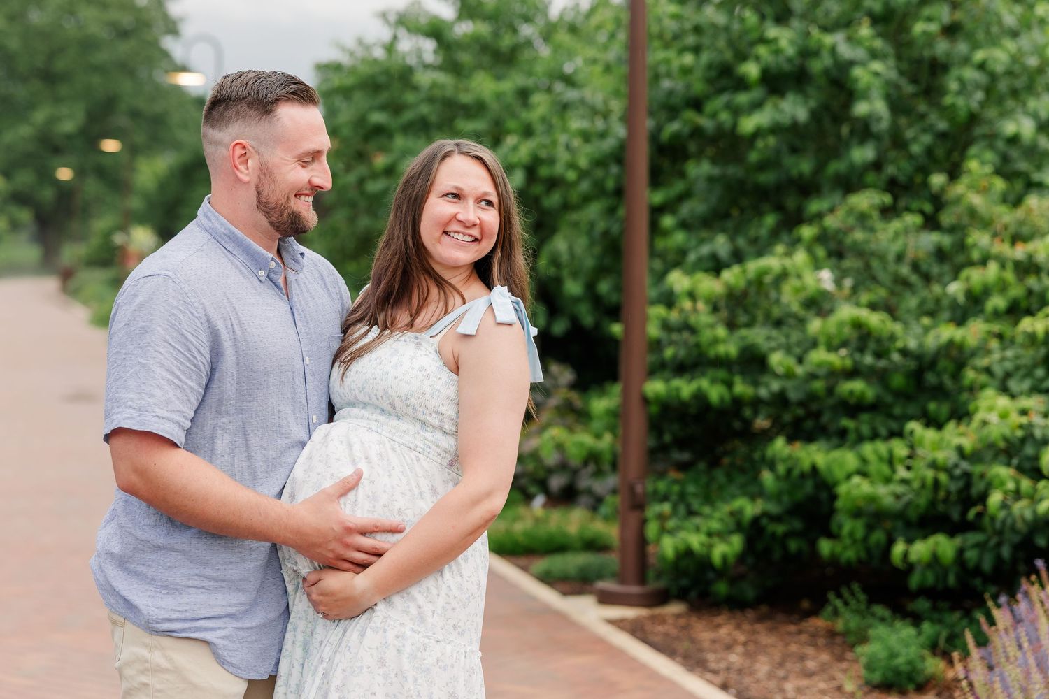 Expecting parents holding a baby bump during a sweet garden maternity session