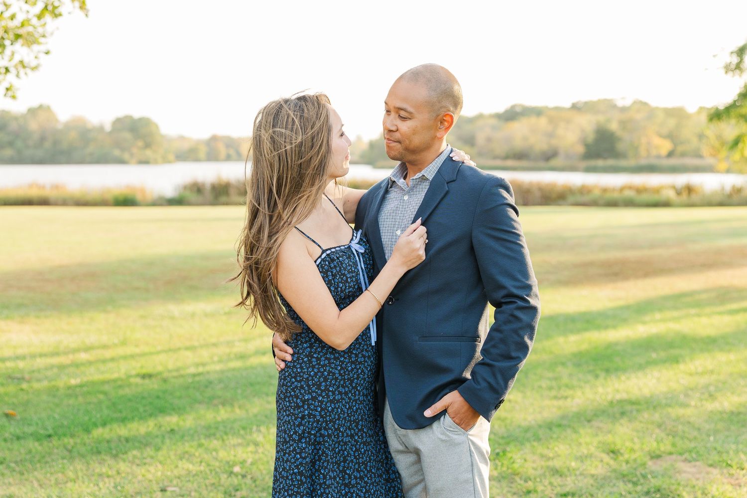 A couple shares a romantic moment together in a sunlit field during their engagement photo session. Busse Woods