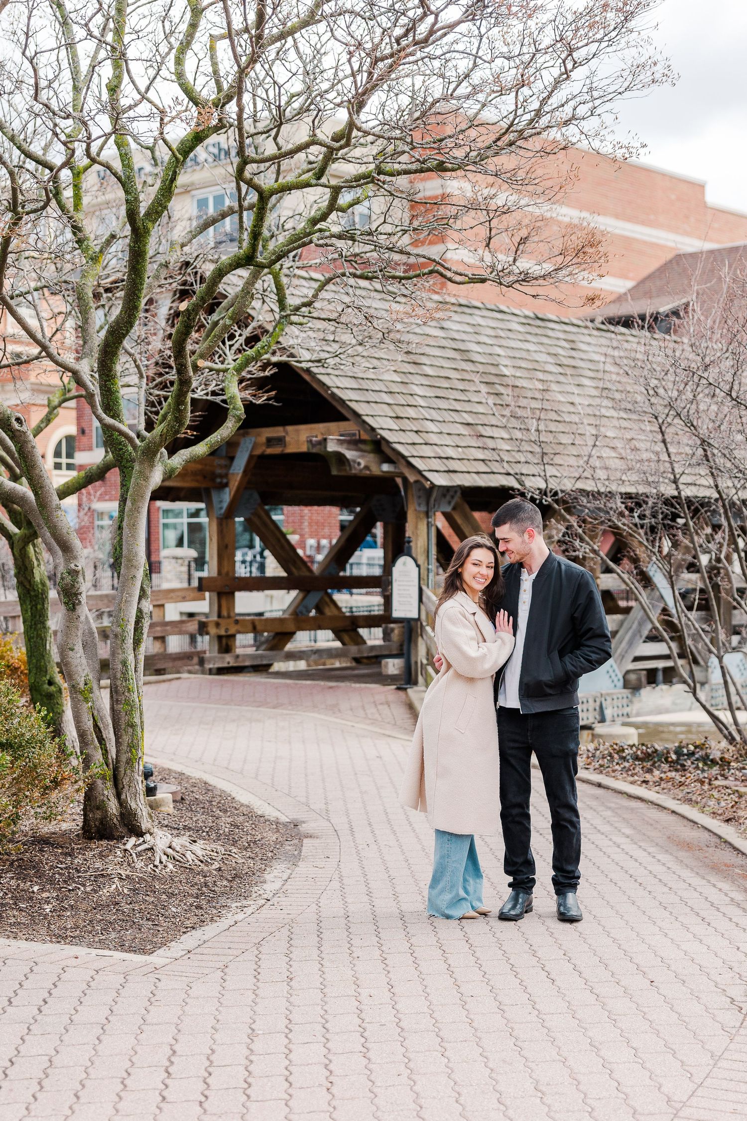 A sweet moment shared between a couple by a wooden gazebo on a brick-lined path.