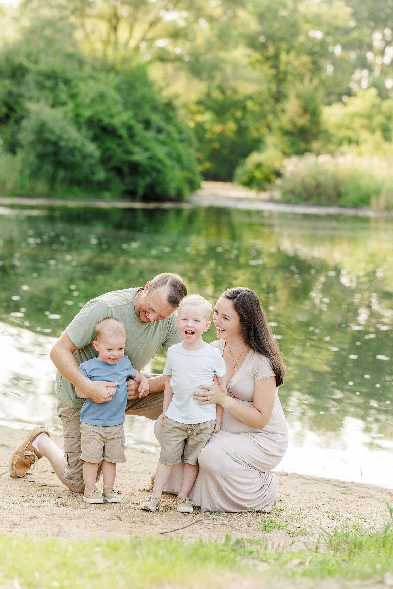 A family shares joyful moments together by a serene pond on a sunny summer afternoon.