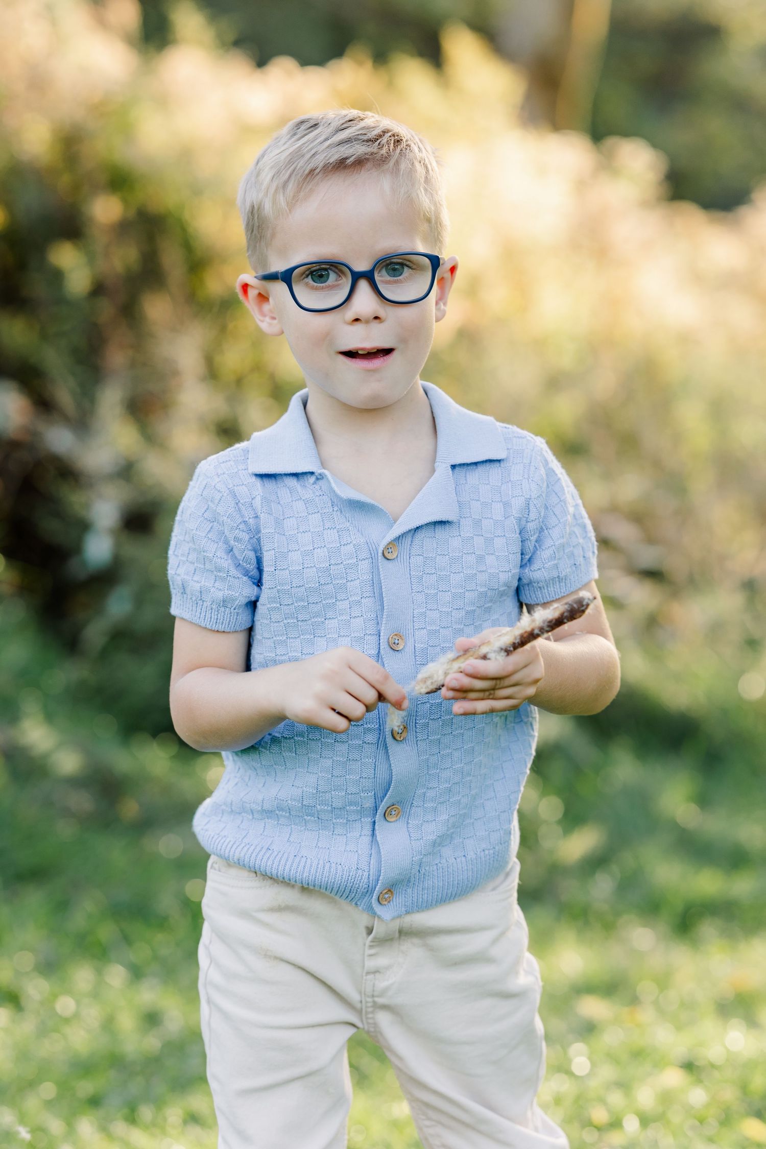 Boy wearing glasses and a blue shirt during a backyard portrait session in St. Charles, IL.