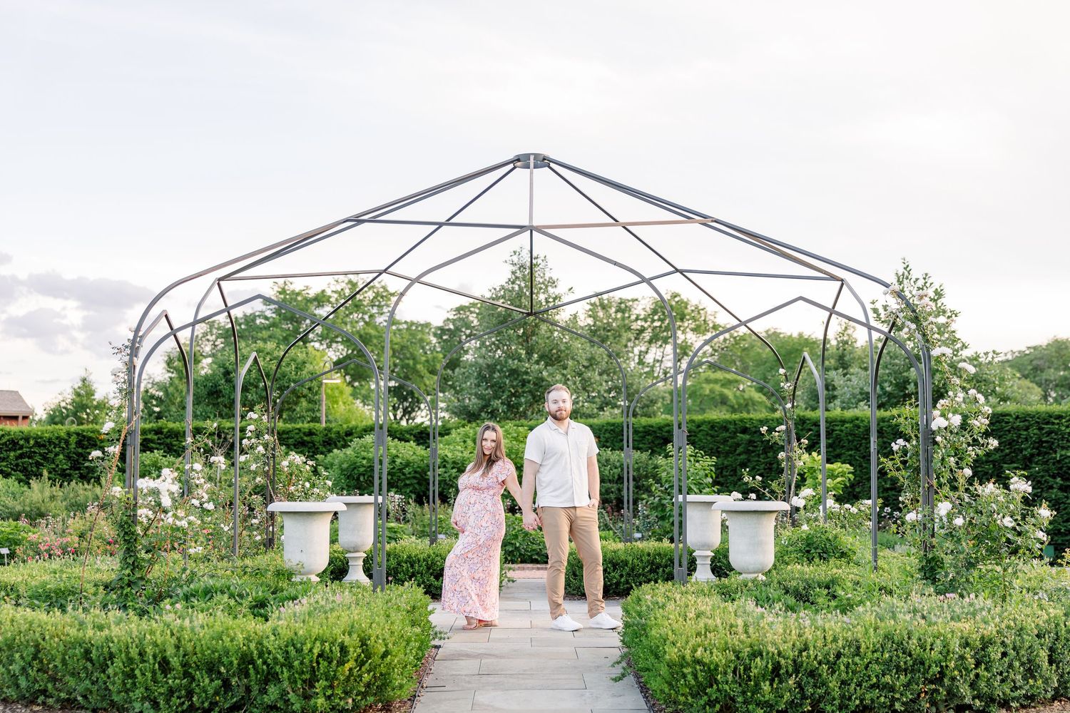 Classic maternity portrait of expecting parents standing under the garden arch at Cantigny Park in Wheaton