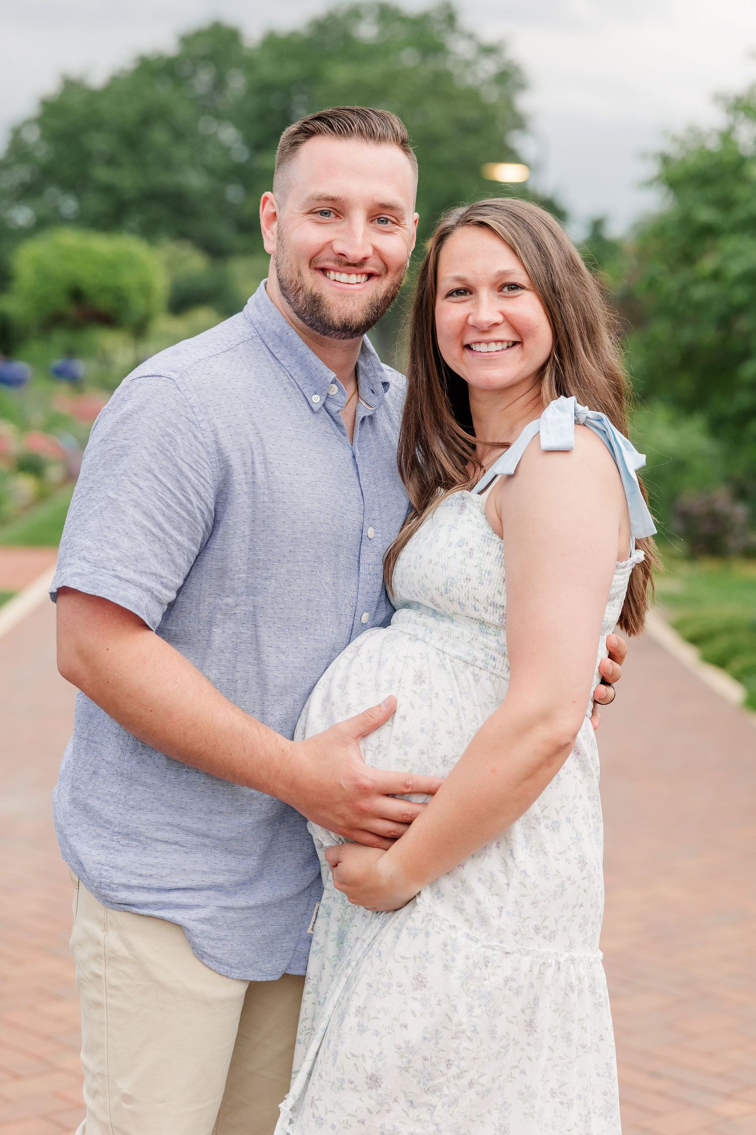 Expecting parents smiling together on a garden path during their Cantigny maternity photos