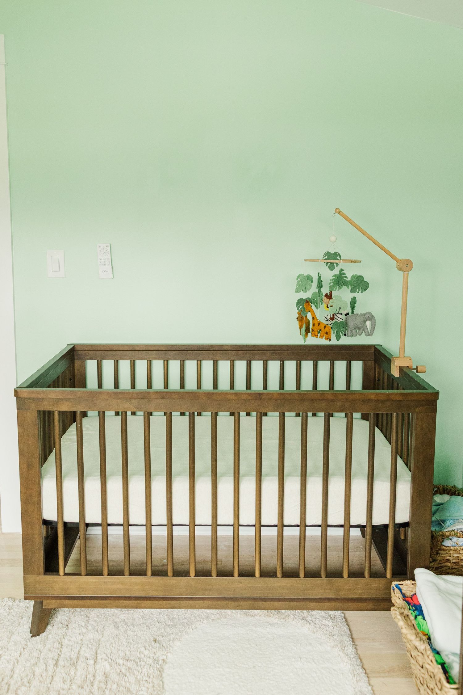 Wood crib in soft green baby nursery photographed during an in-home lifestyle newborn session in Palatine IL
