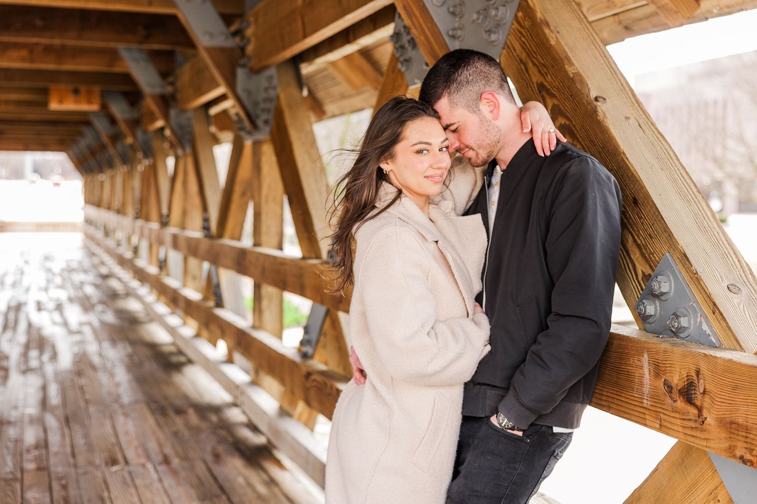 Romantic couple embracing in winter inside covered wooden bridge.