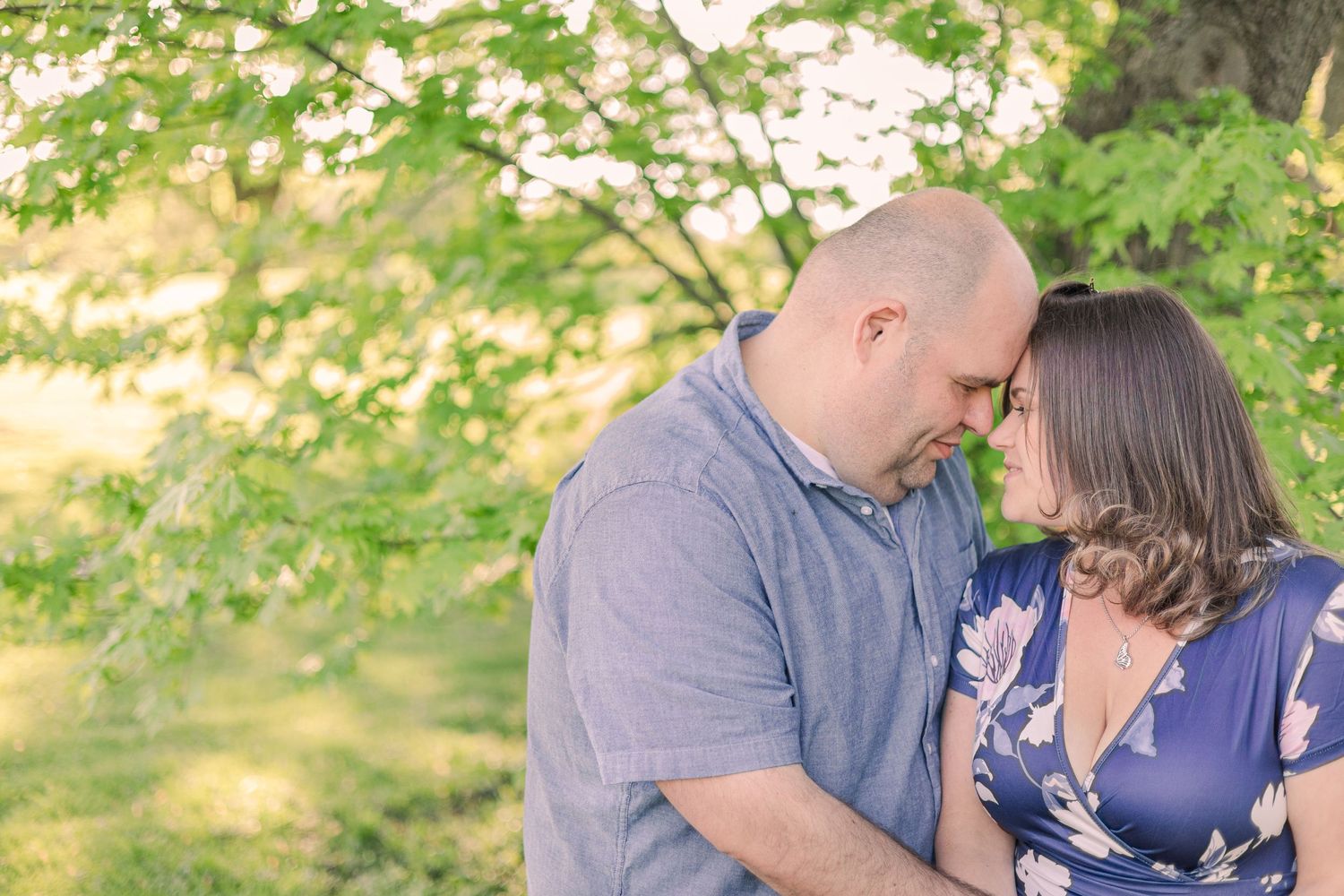 Intimate couple moment captured against blurred green garden backdrop.