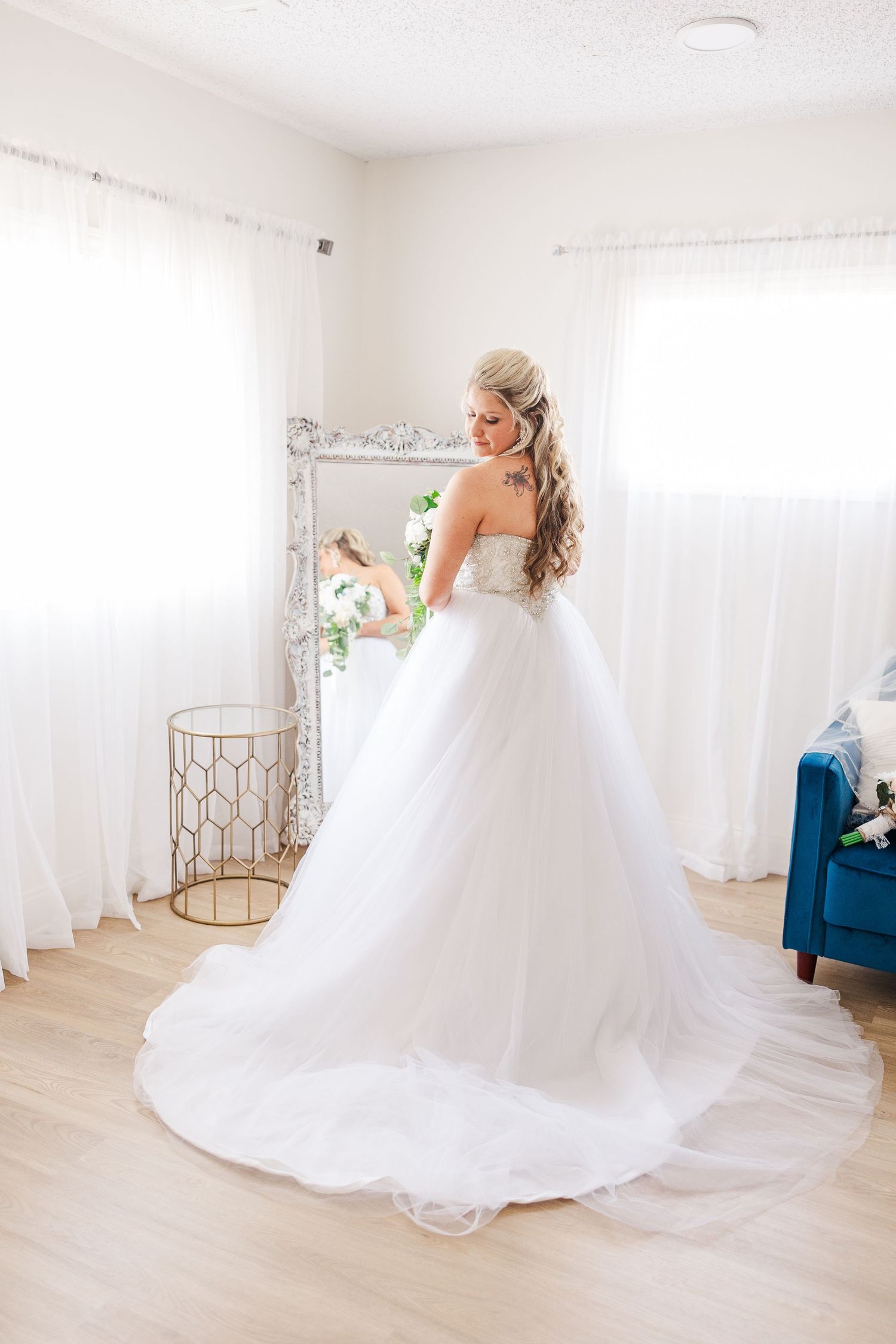 A flowing white ballgown wedding dress captured in a bright room with an ornate mirror.