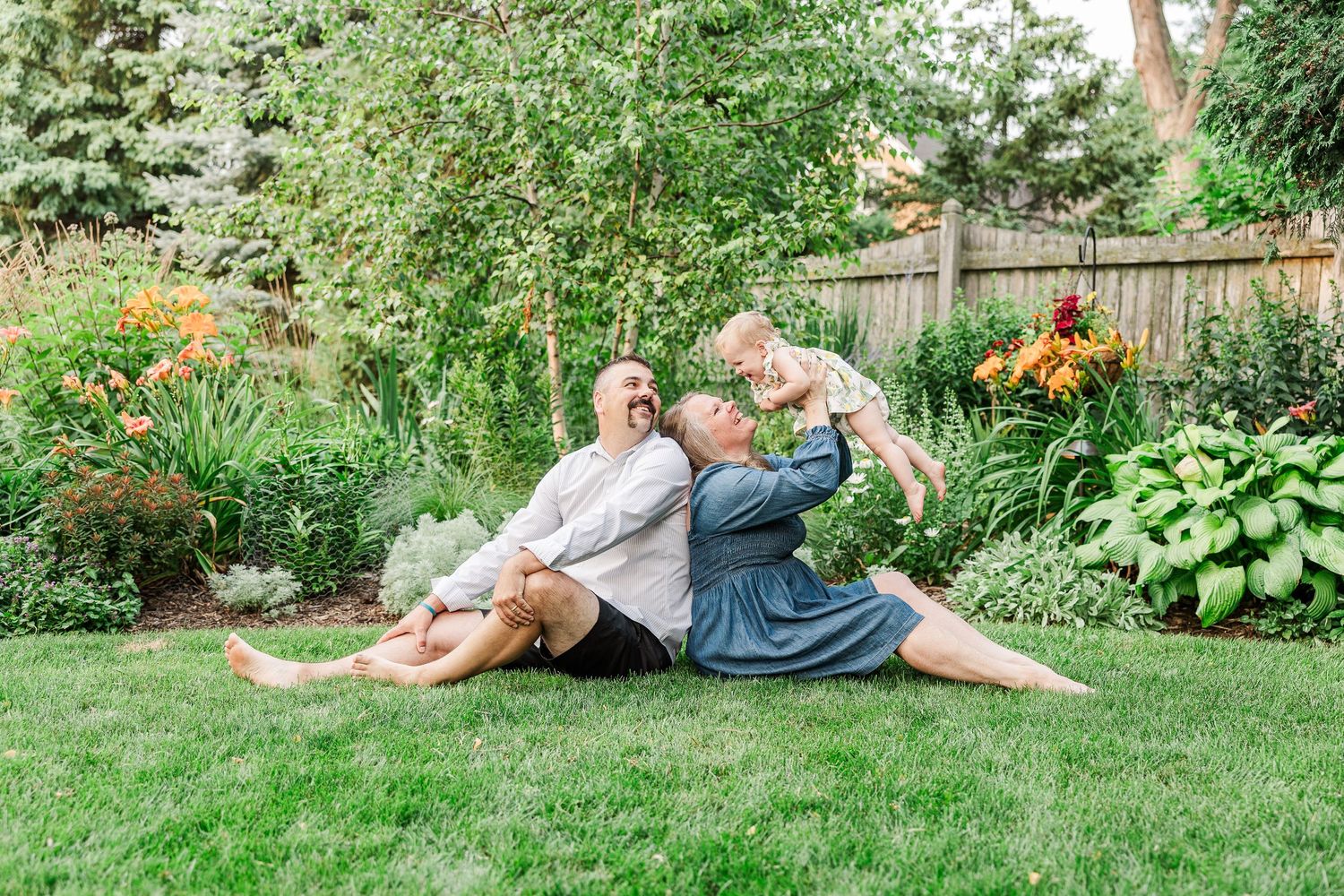 A couple relaxes together on green grass in a vibrant summer garden.