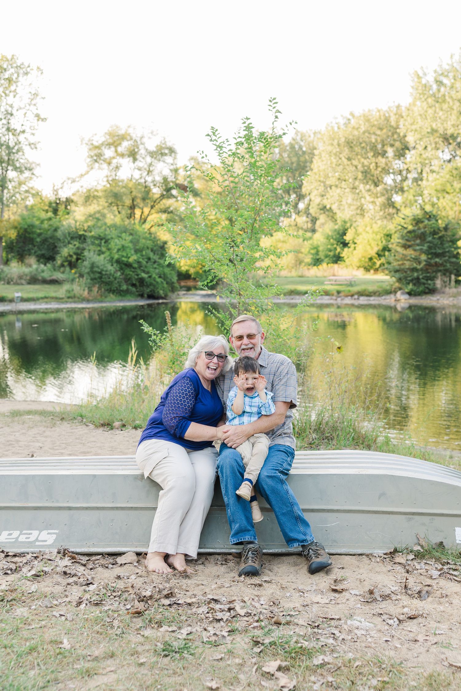 Family enjoying an autumn afternoon together while sitting at the edge of a tranquil pond.Sorg family portraits at Shamrock Hills Park in Cr