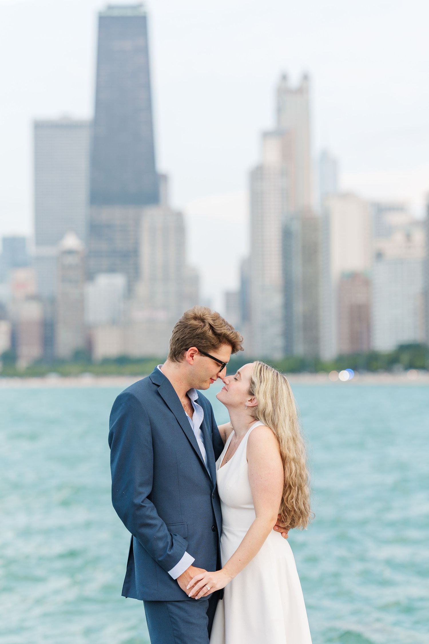 Elizabeth and Joe holding hands with the Chicago skyline in the background at North Avenue Beach during sunset