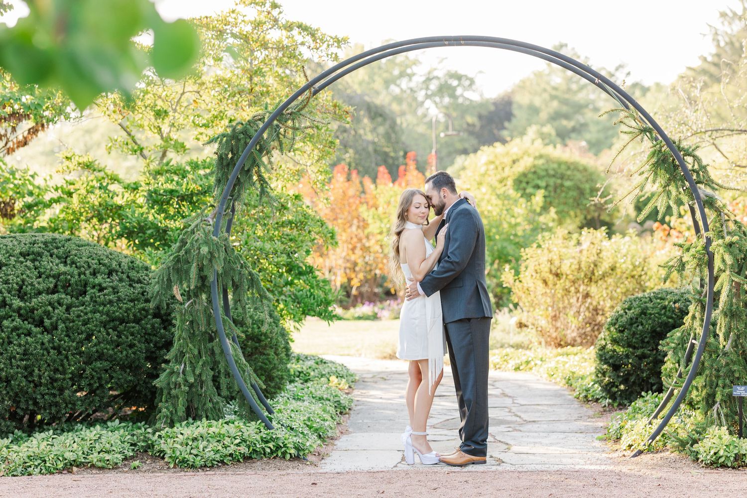 Couple embracing beneath garden arch during engagement photos at Cantigny Park
