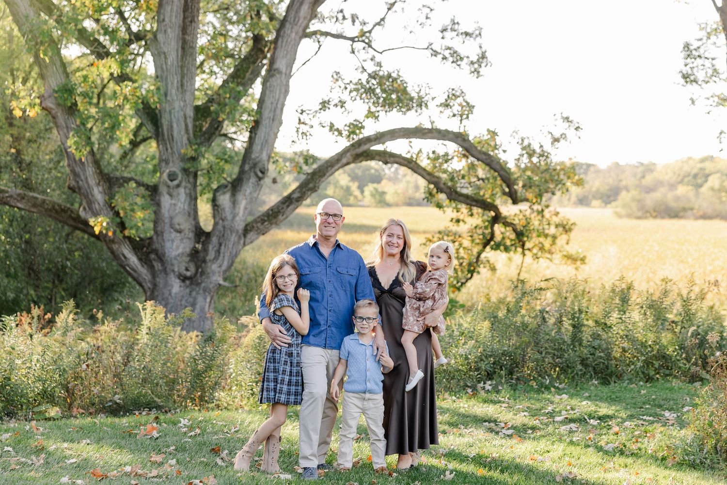Family of five beneath a backyard tree during fall family photos in St. Charles, IL.