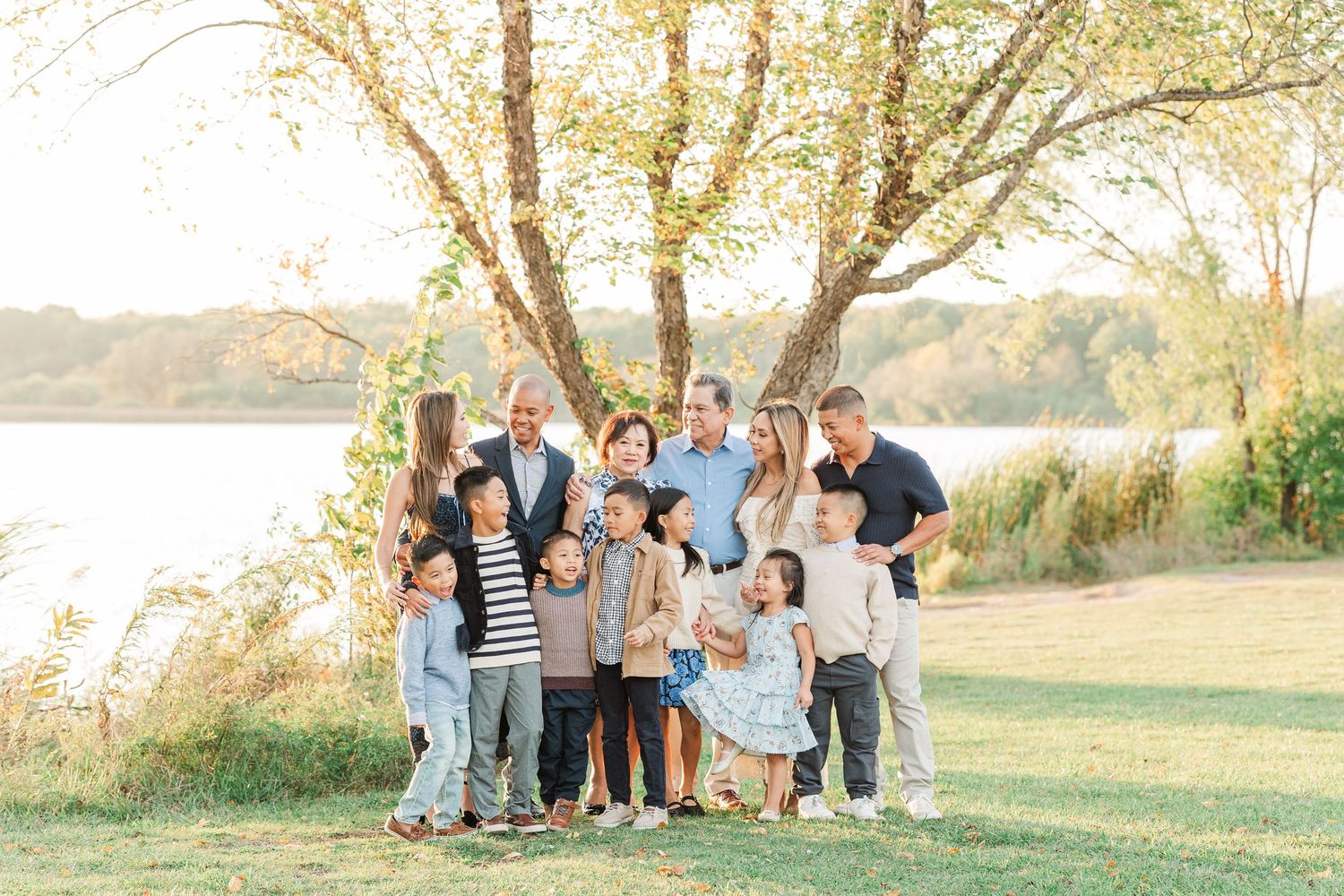 A group gathers outdoors in a golden field during sunset for casual family portraits.