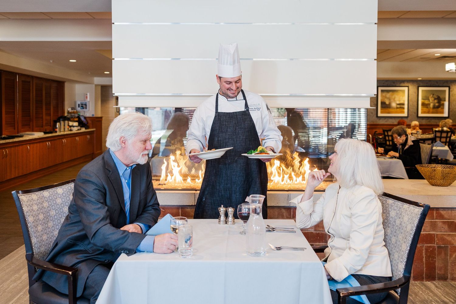 Beacon Hill senior living branding photo in Lombard, Illinois featuring chef serving residents at table