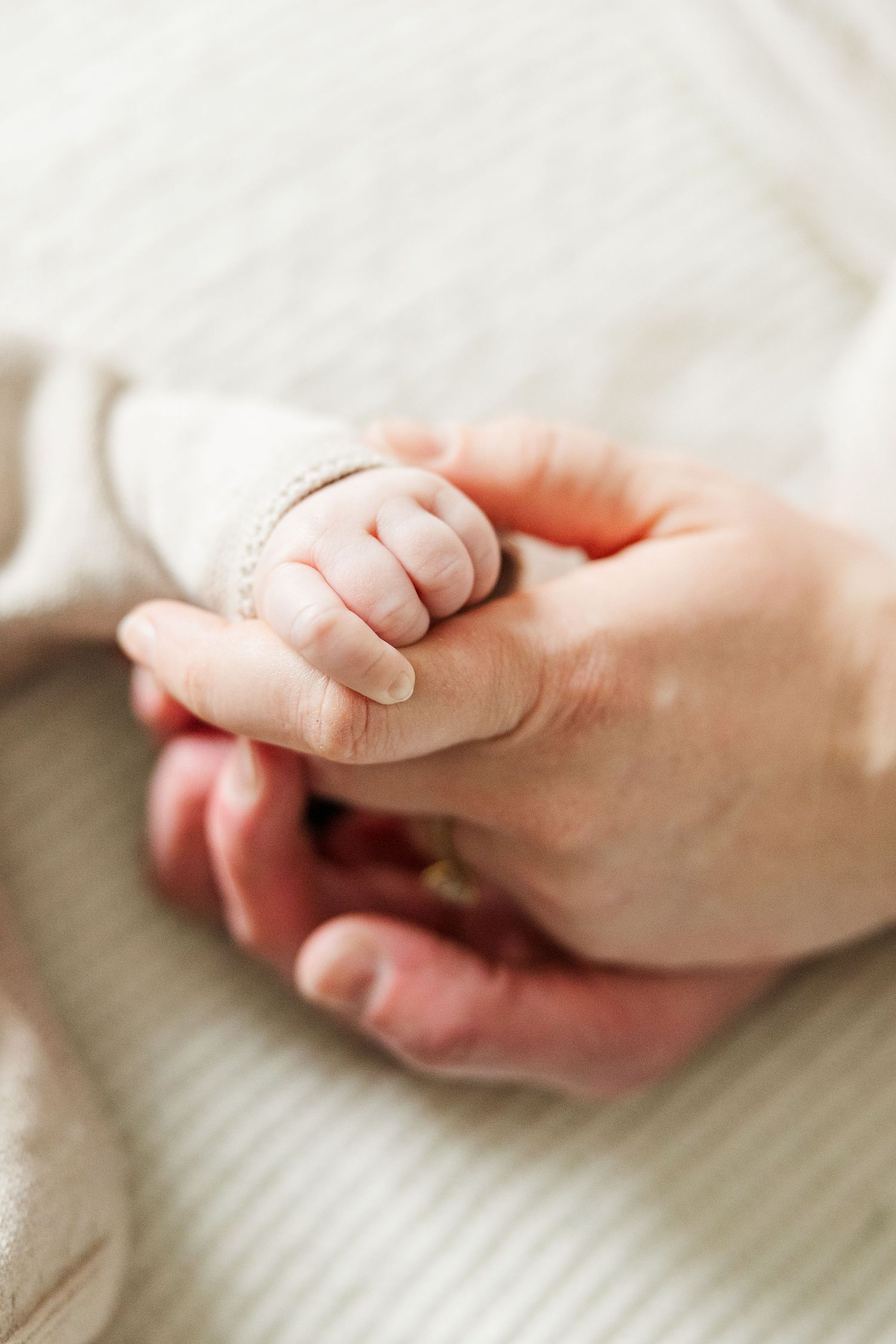 Close-up of a newborn baby holding a parent’s finger during an in-home lifestyle newborn photography session in Palatine IL