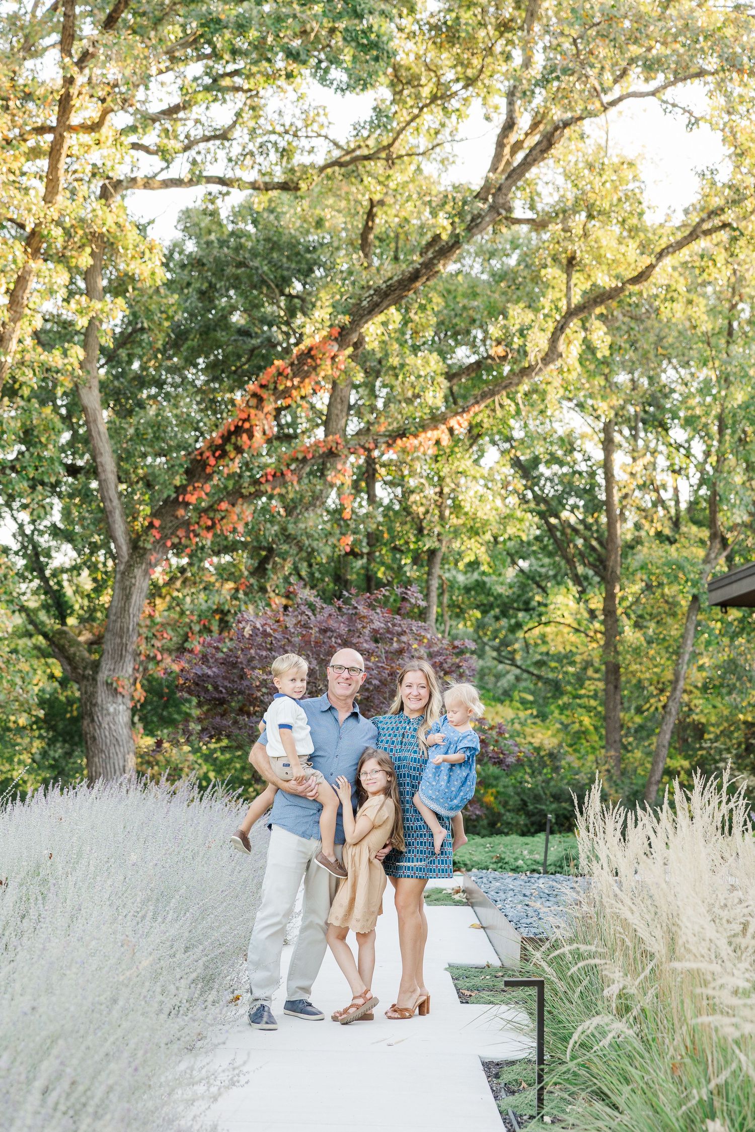 Family portrait session in a natural outdoor setting with tall grasses and trees during golden hour.