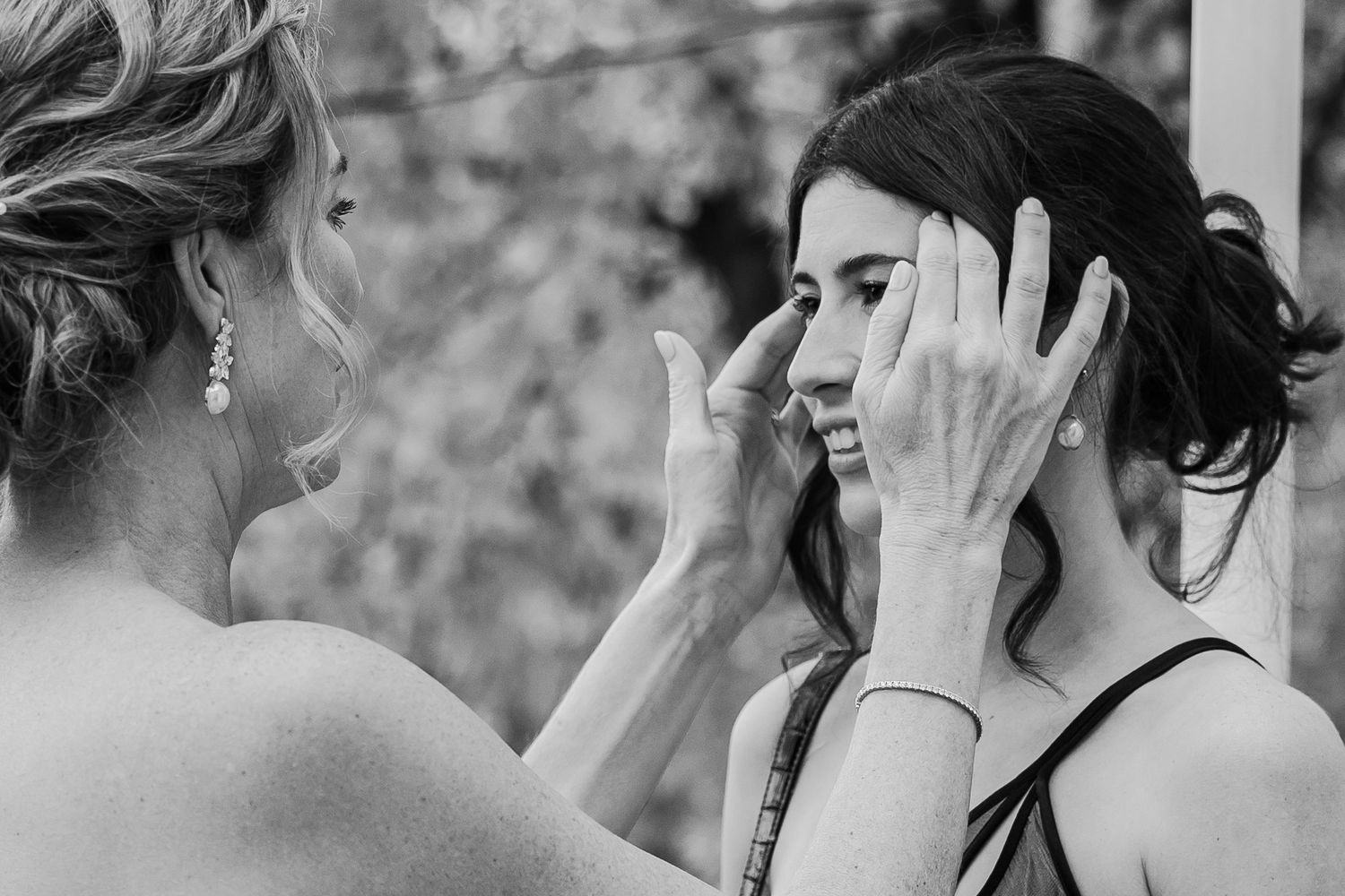 Black and white emotional moment between two women, one wiping tears from the other's face.