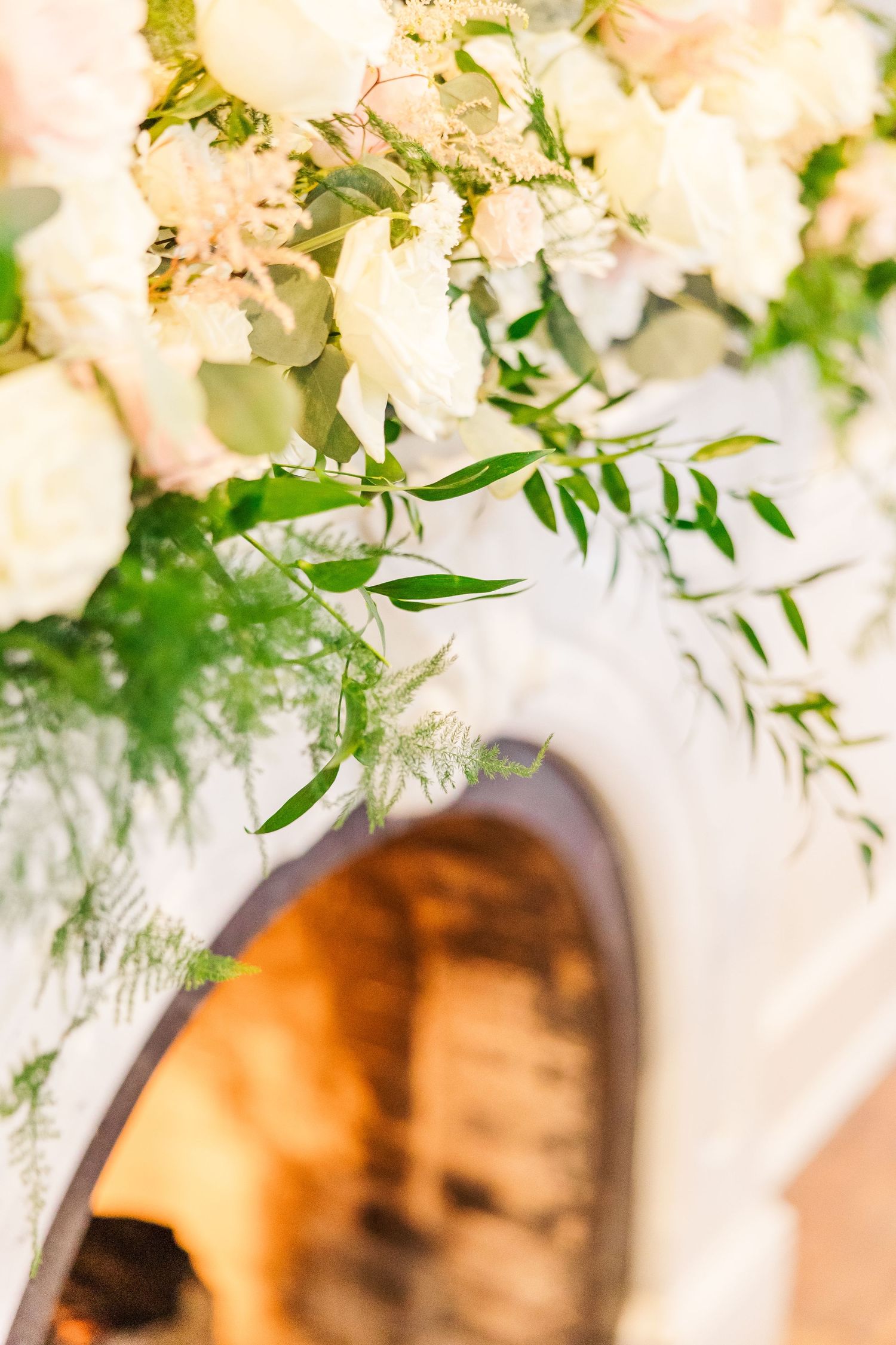Soft focus arrangement of white flowers and greenery against blurred background.