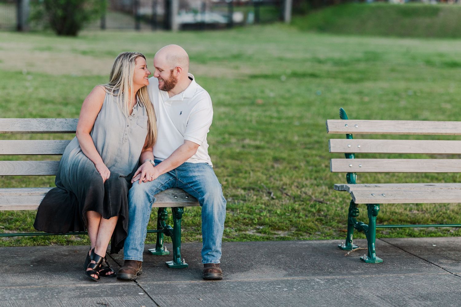 A couple shares an intimate moment while sitting together on a park bench.