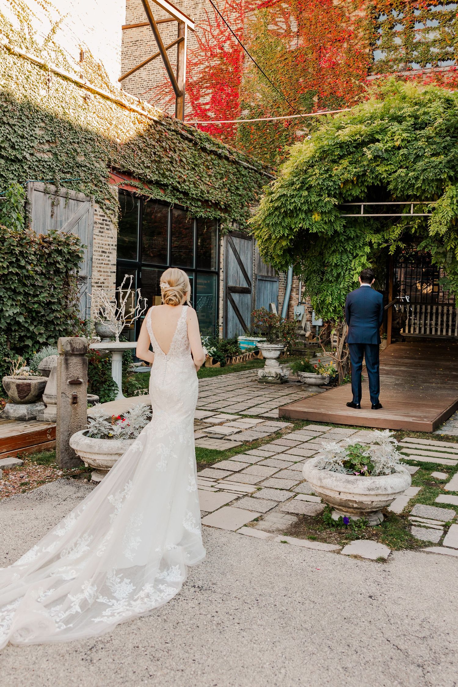 First look wedding moment in a garden courtyard with ivy-covered walls and stone pathways.