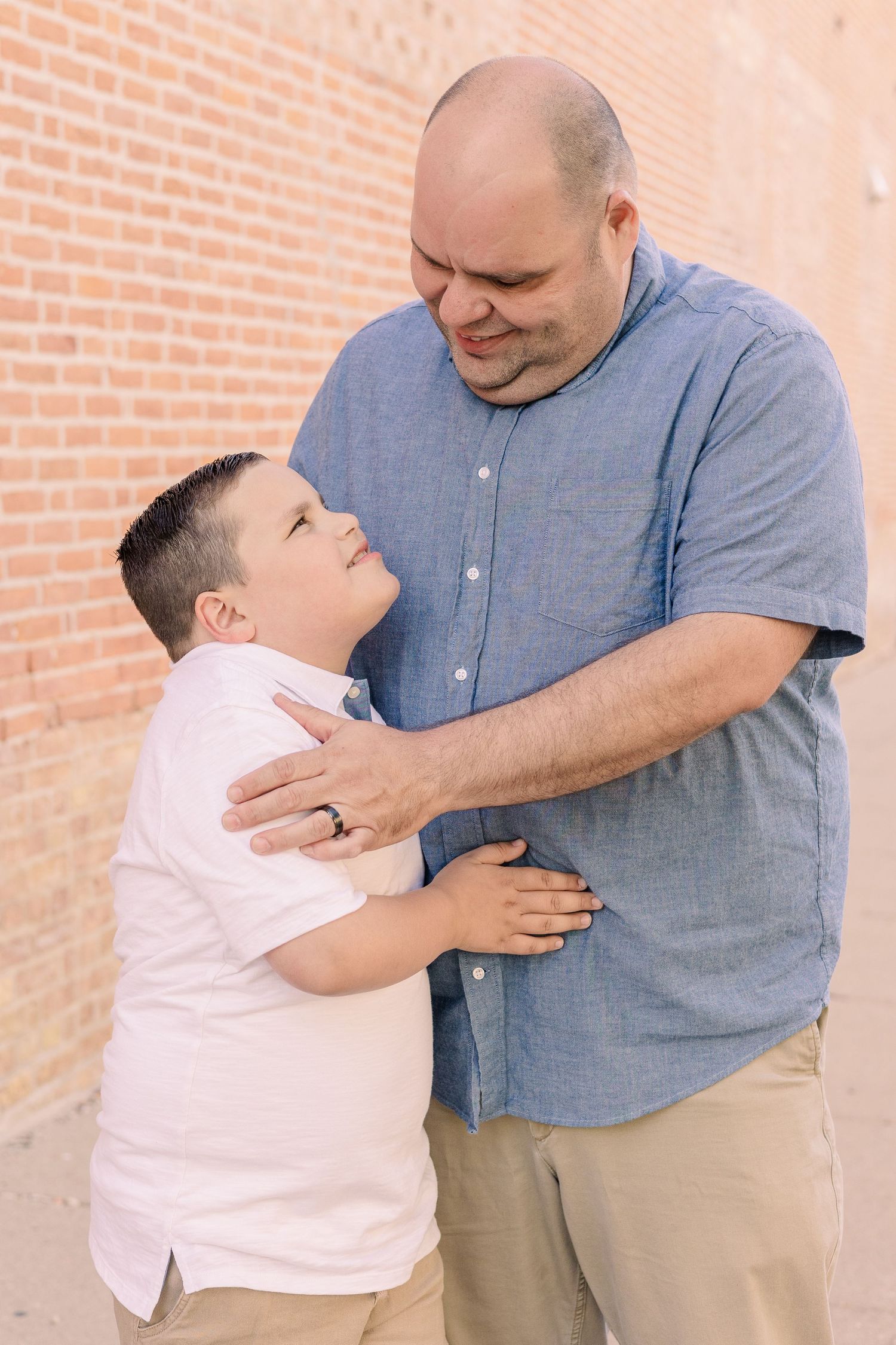 An intimate portrait showing affection between two people against a brick wall.