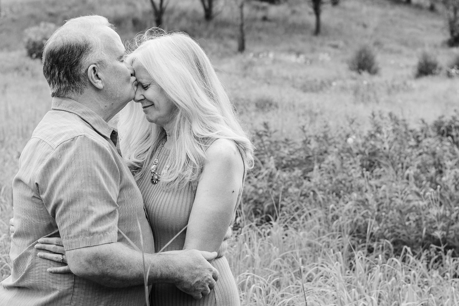 A romantic black and white portrait of a couple sharing an intimate moment in nature.