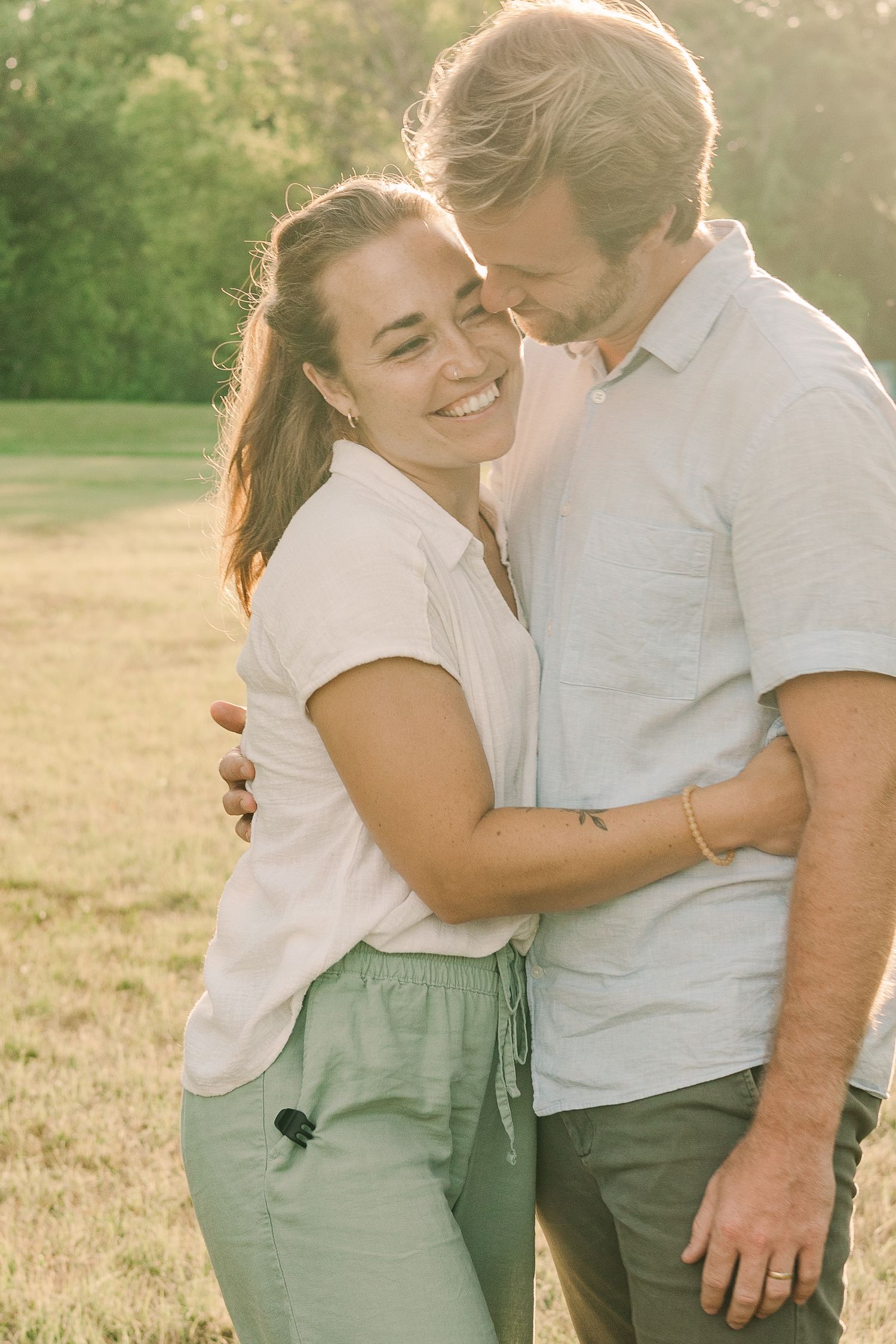 Tender embrace between couple sharing a laugh in warm sunset light.
