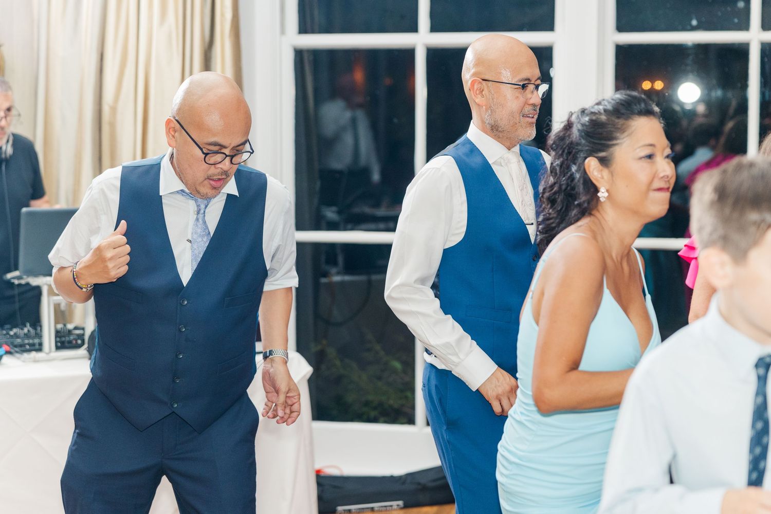 Wedding guests dancing and celebrating on the dance floor during an evening reception.