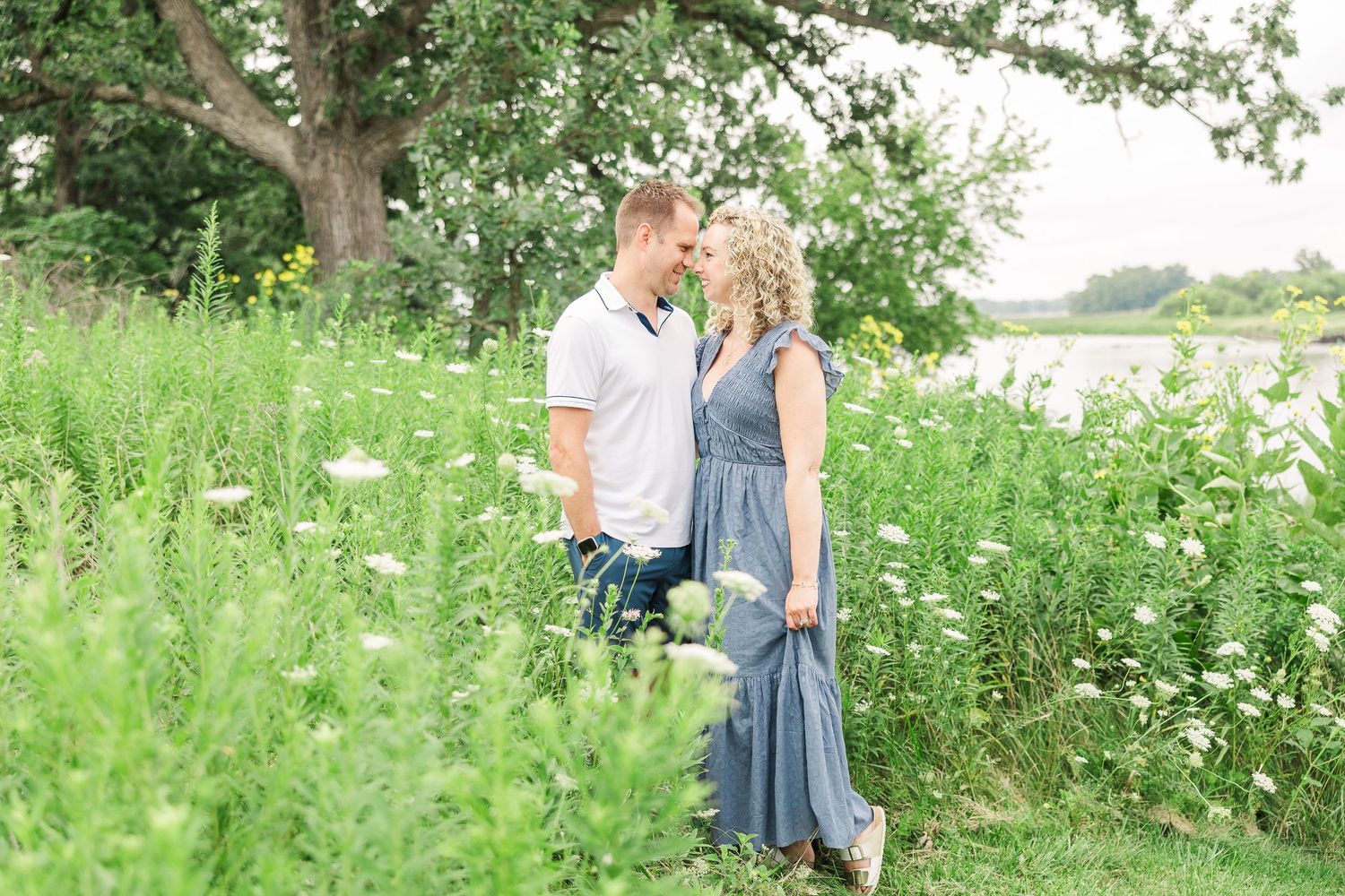A couple enjoying a romantic moment in a wildflower meadow near the water.