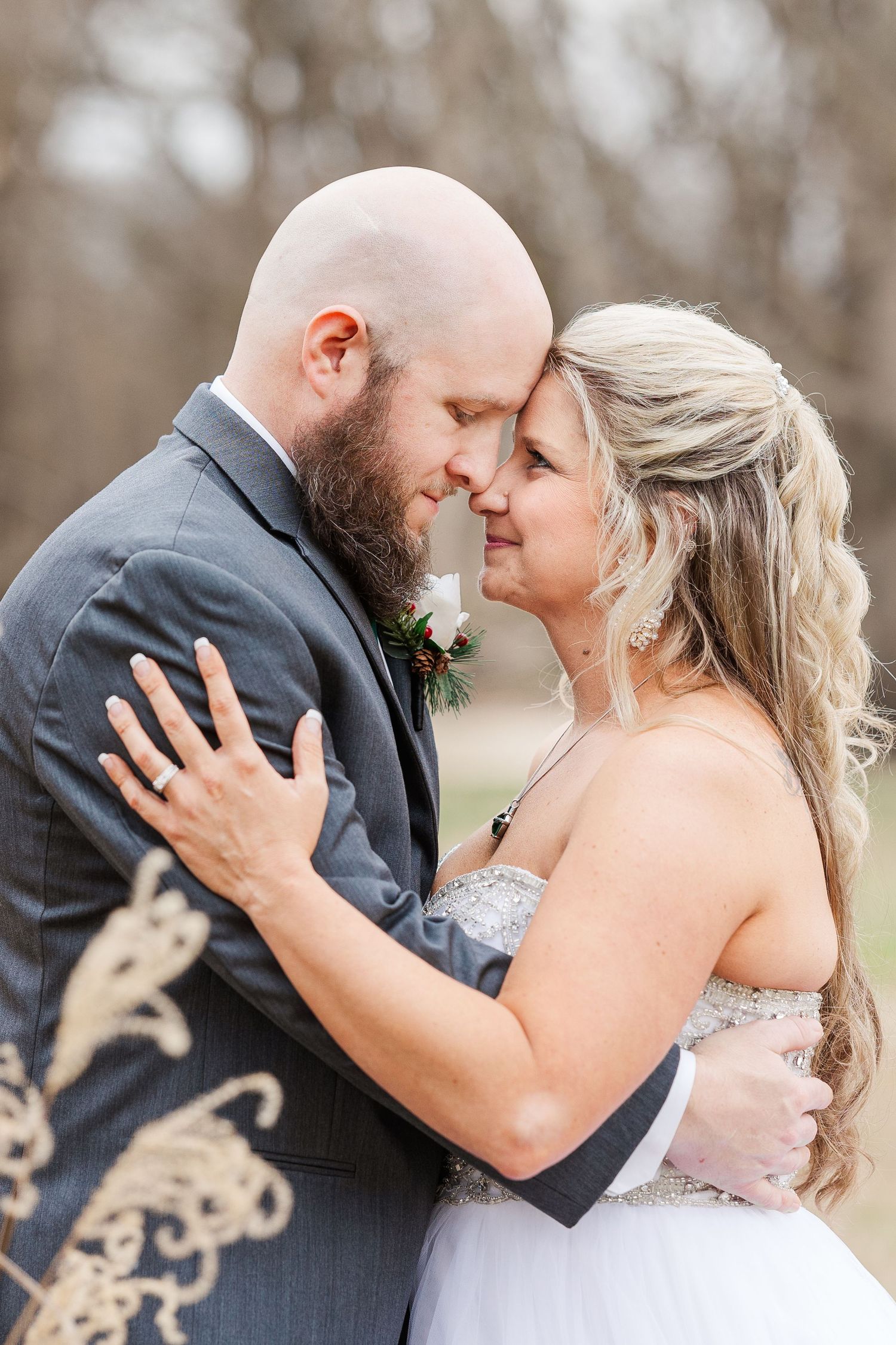 Intimate wedding portrait showing a tender moment between newlyweds in a rustic outdoor setting.