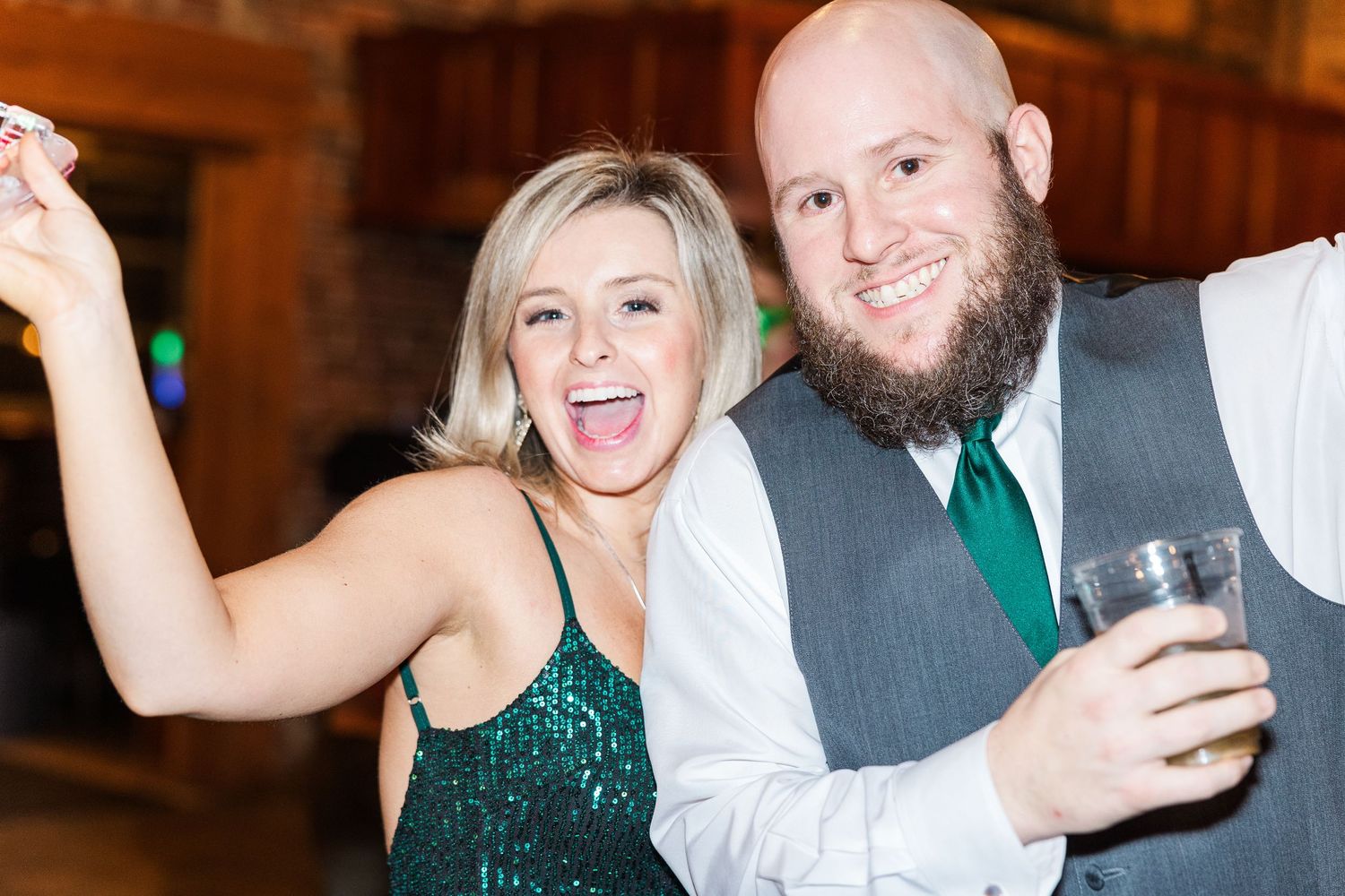 Guests celebrating at wedding reception with drinks in rustic venue.
