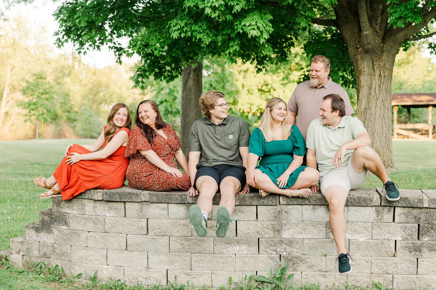 Friends and family relaxing together on concrete steps under a large tree.