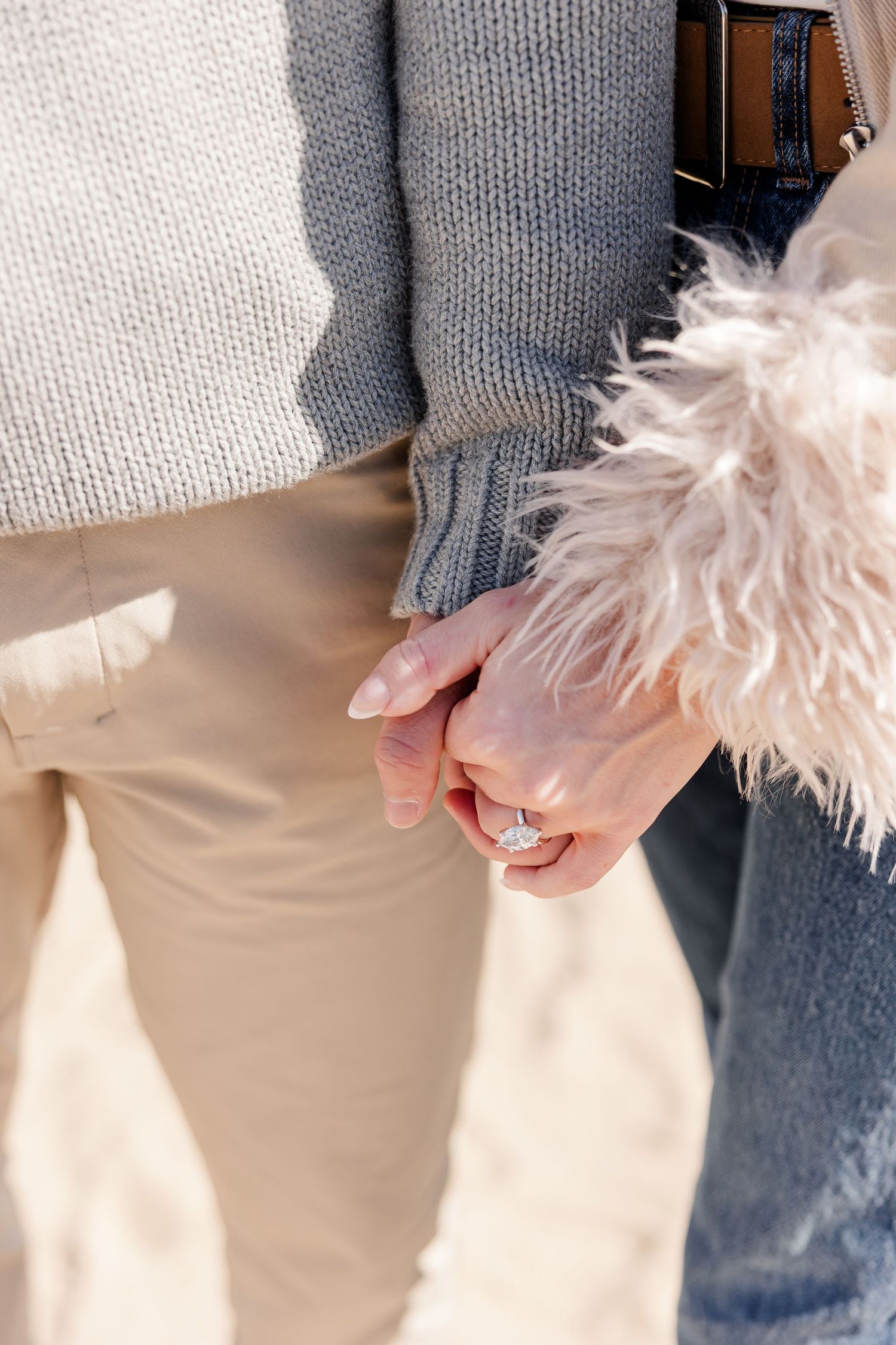 Close-up of couple holding hands showing diamond engagement ring.