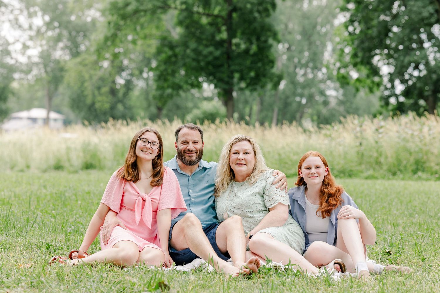 Cousins sitting together in the grass during a summer extended family session in Crystal Lake, IL.