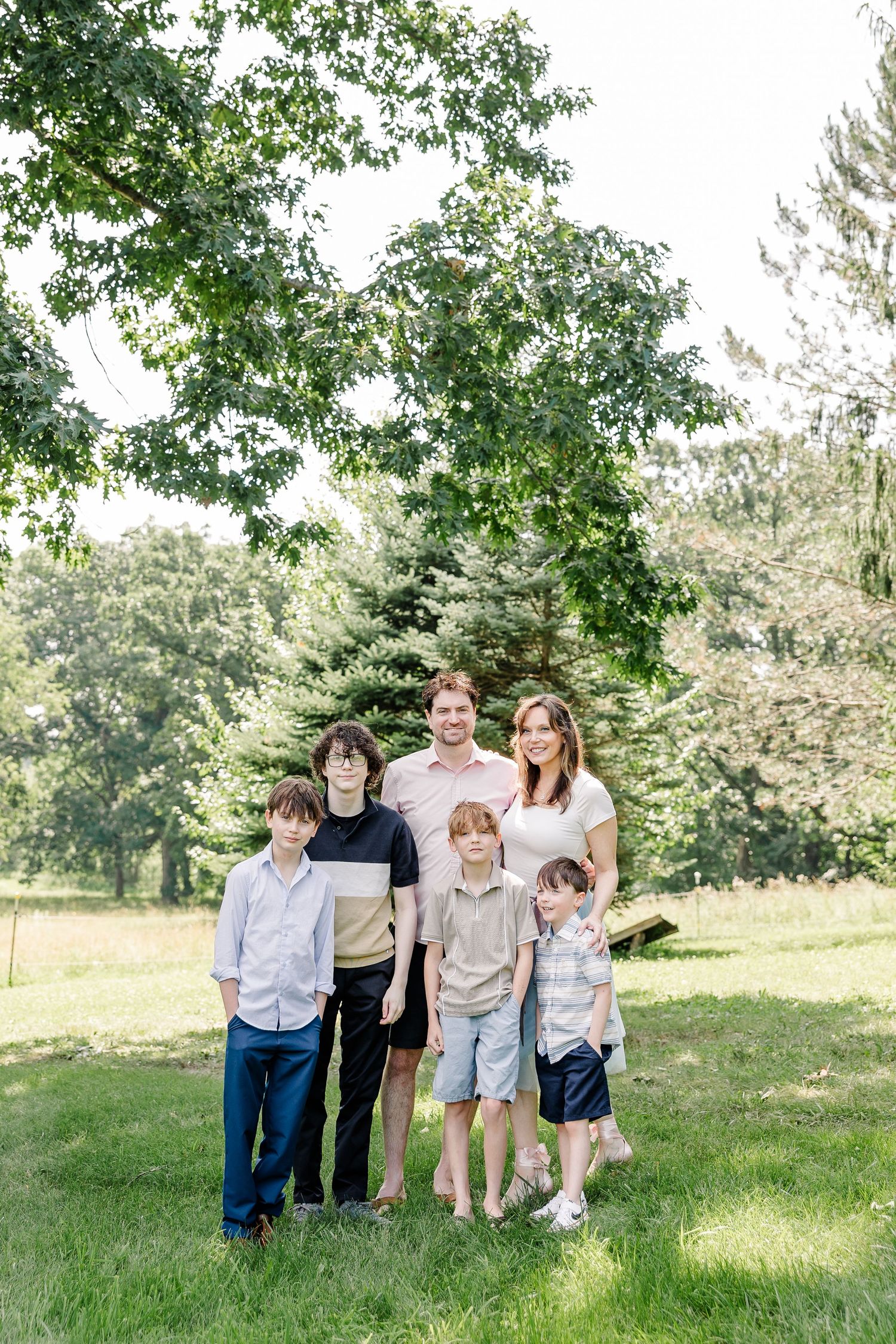 Family portrait under tall trees during a summer extended family session in Crystal Lake, IL.