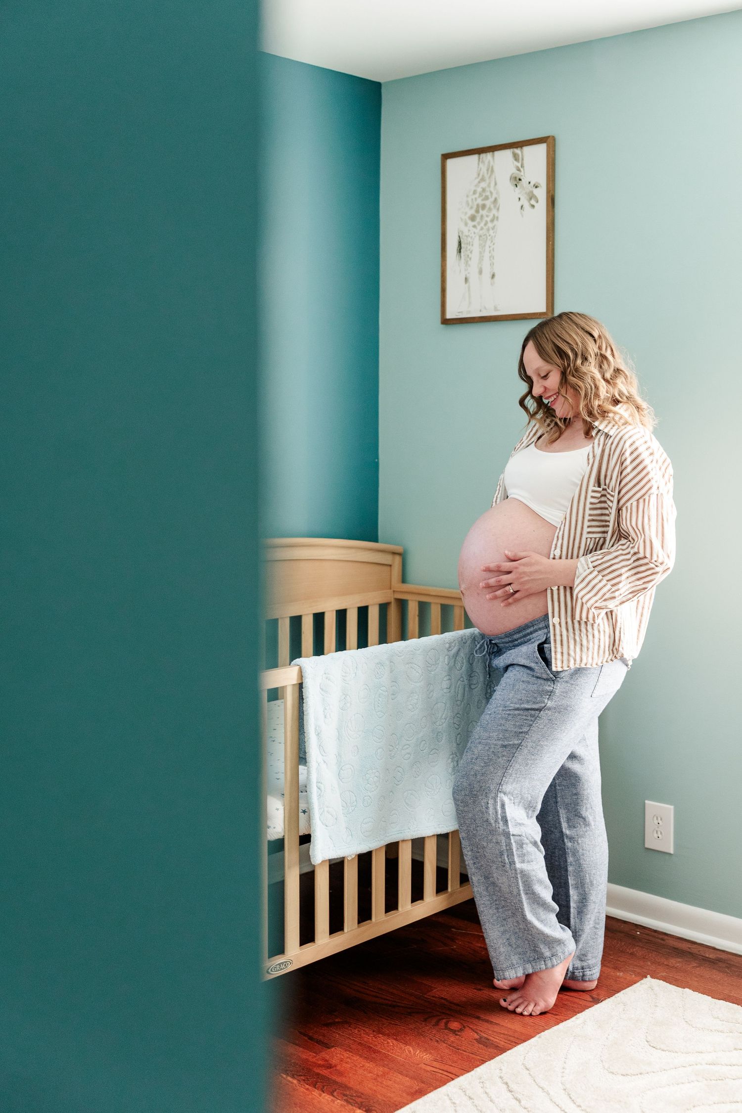 Mother holding baby bump in twin boys’ nursery during an in-home maternity session in Crystal Lake.