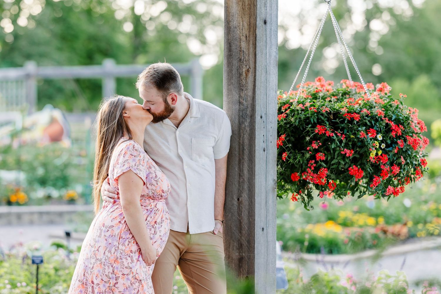 Parents-to-be holding hands and walking under a trellis during a Cantigny maternity session in Wheaton