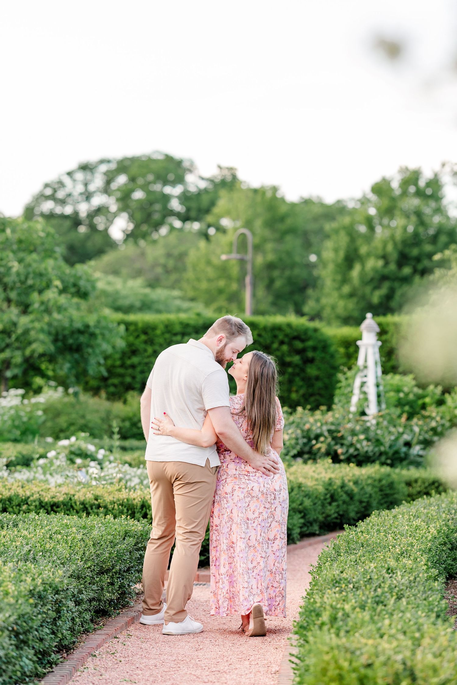 Expecting parents sharing a kiss in the formal gardens during their Cantigny maternity session in Wheaton