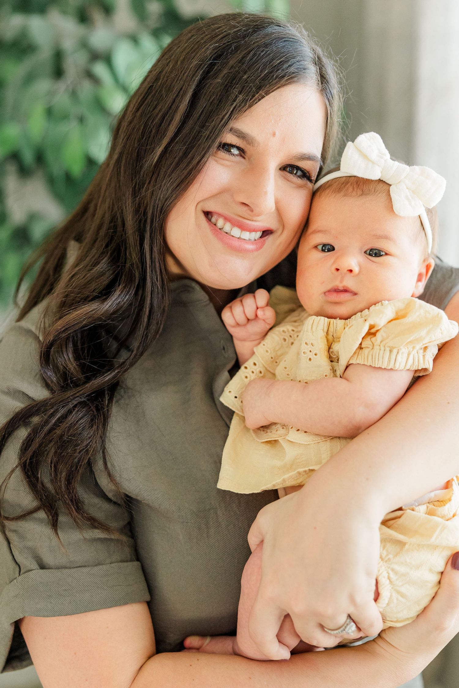 Mom smiling with baby girl in her arms during a bright in-home lifestyle newborn session