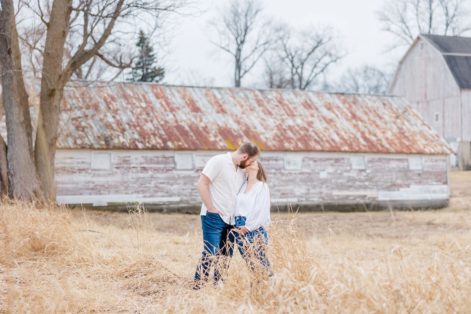 Couple embracing in tall grass during pregnancy announcement photos in Cary, Illinois